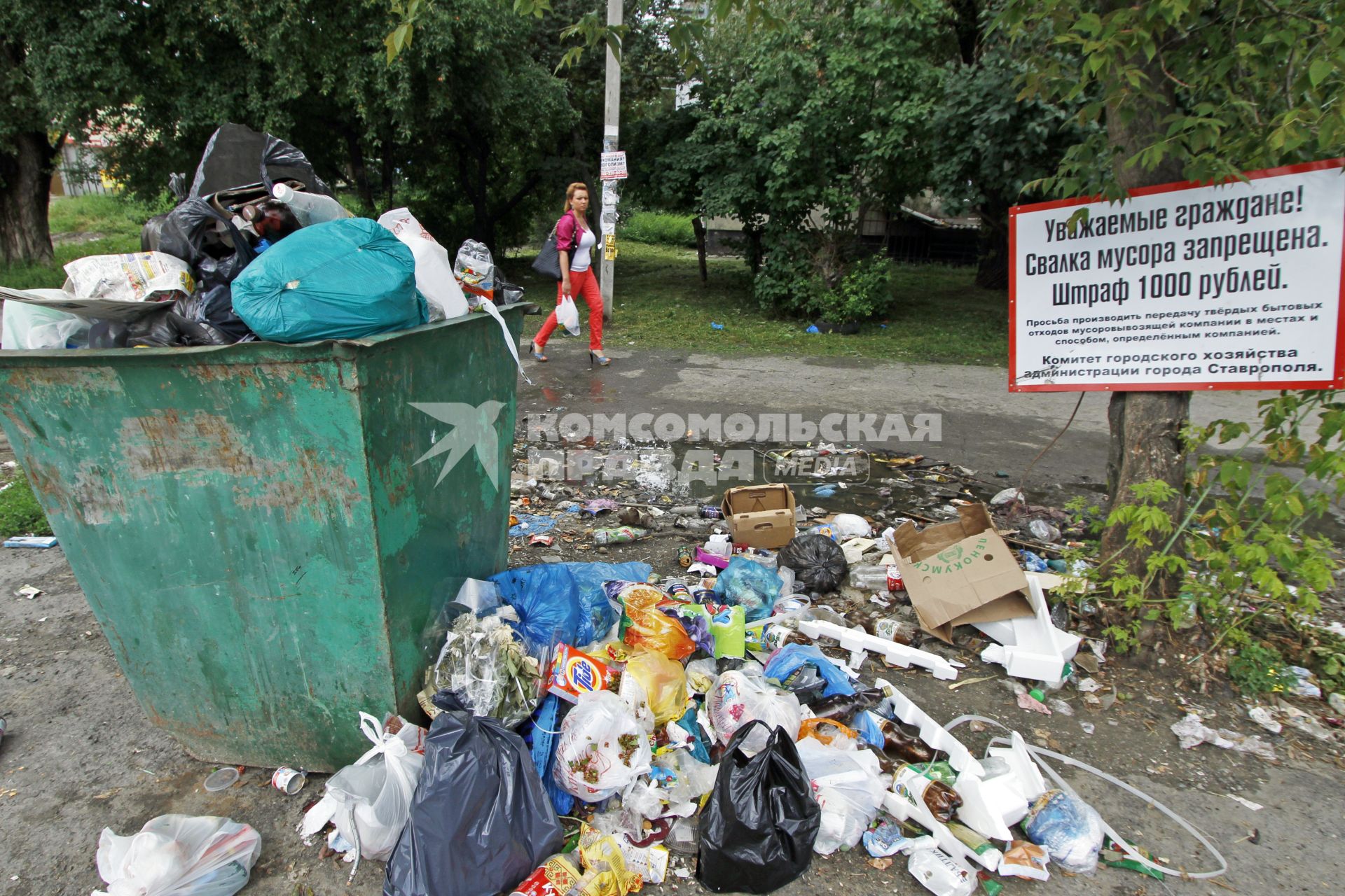 Мусорка в Ставрополе. Мусор вываливается из мусорки напротив плаката о запрете свалки.