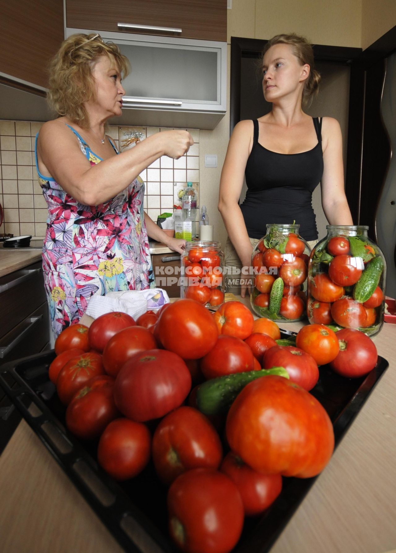 Домашнее консервирование.  На снимке: женщины укладывают овощи в банки.