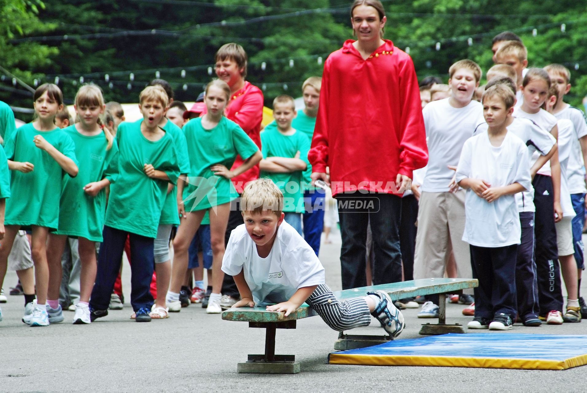 Мальчик ползет по скамейке во время детских соревнований `Веселые старты`.