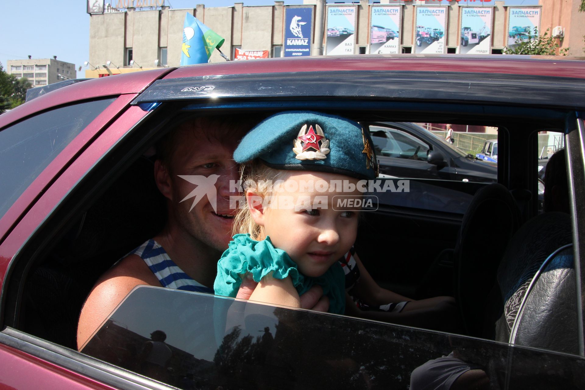 Празднование дня ВДВ в Казани. На снимке: В автомобиле на заднем сидении сидит десантник, у него на коленях сидит девочка ребенок в берете десантника.