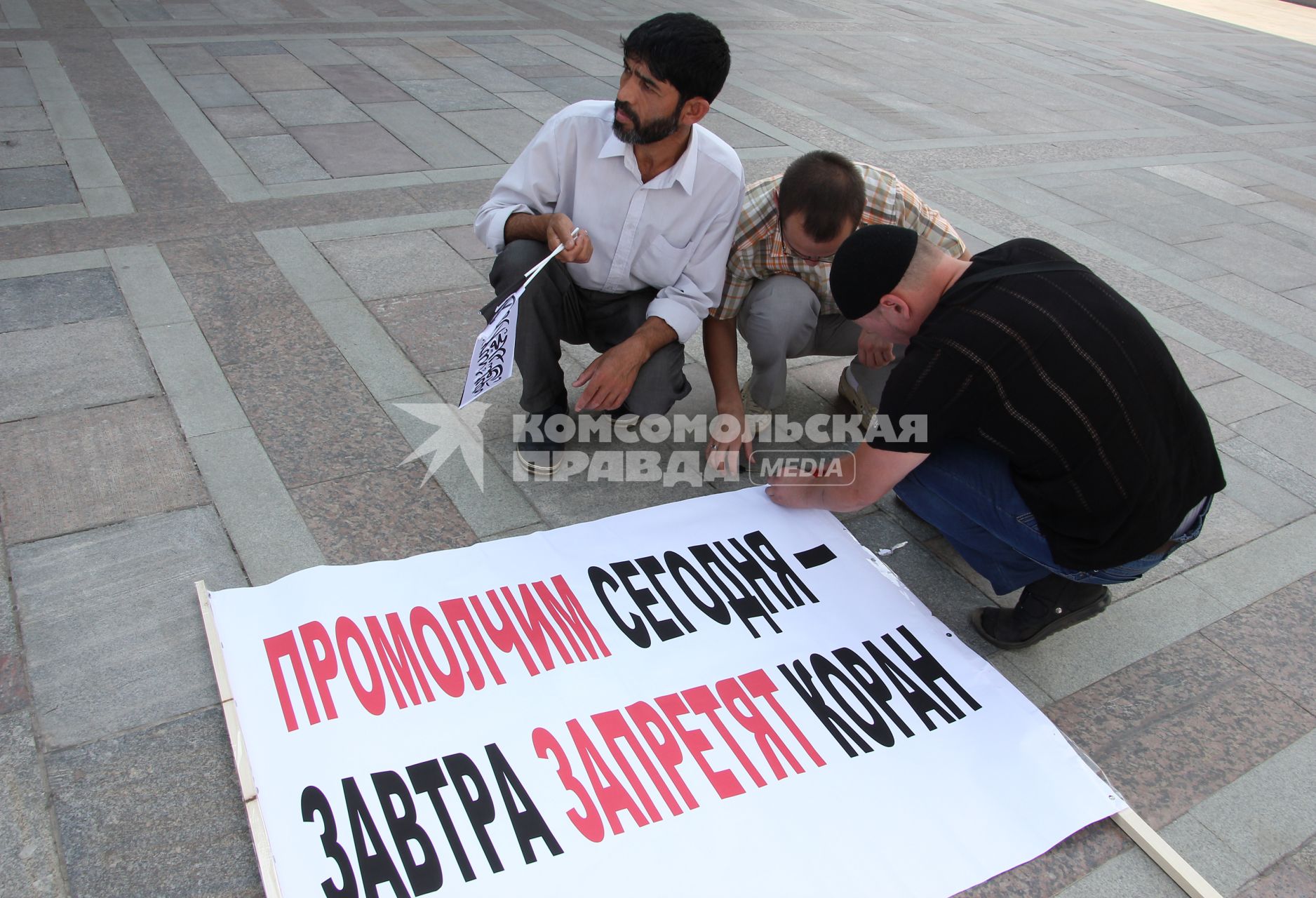 Митинг мусульман против произвола полиции. Площадь театра Камала. Казань. На снимке: Люди прикрепляют плакат с лозунгом: `Промолчим сегодня - завтра запретят коран`.