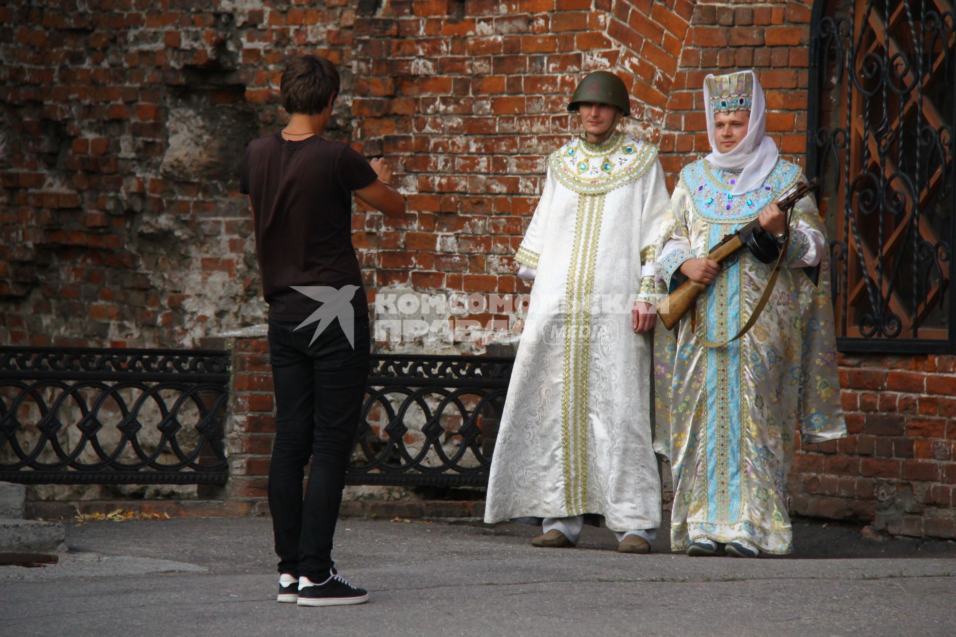 Туристы фотографируются в исторических костюмах на фоне Нижегородского кремля.