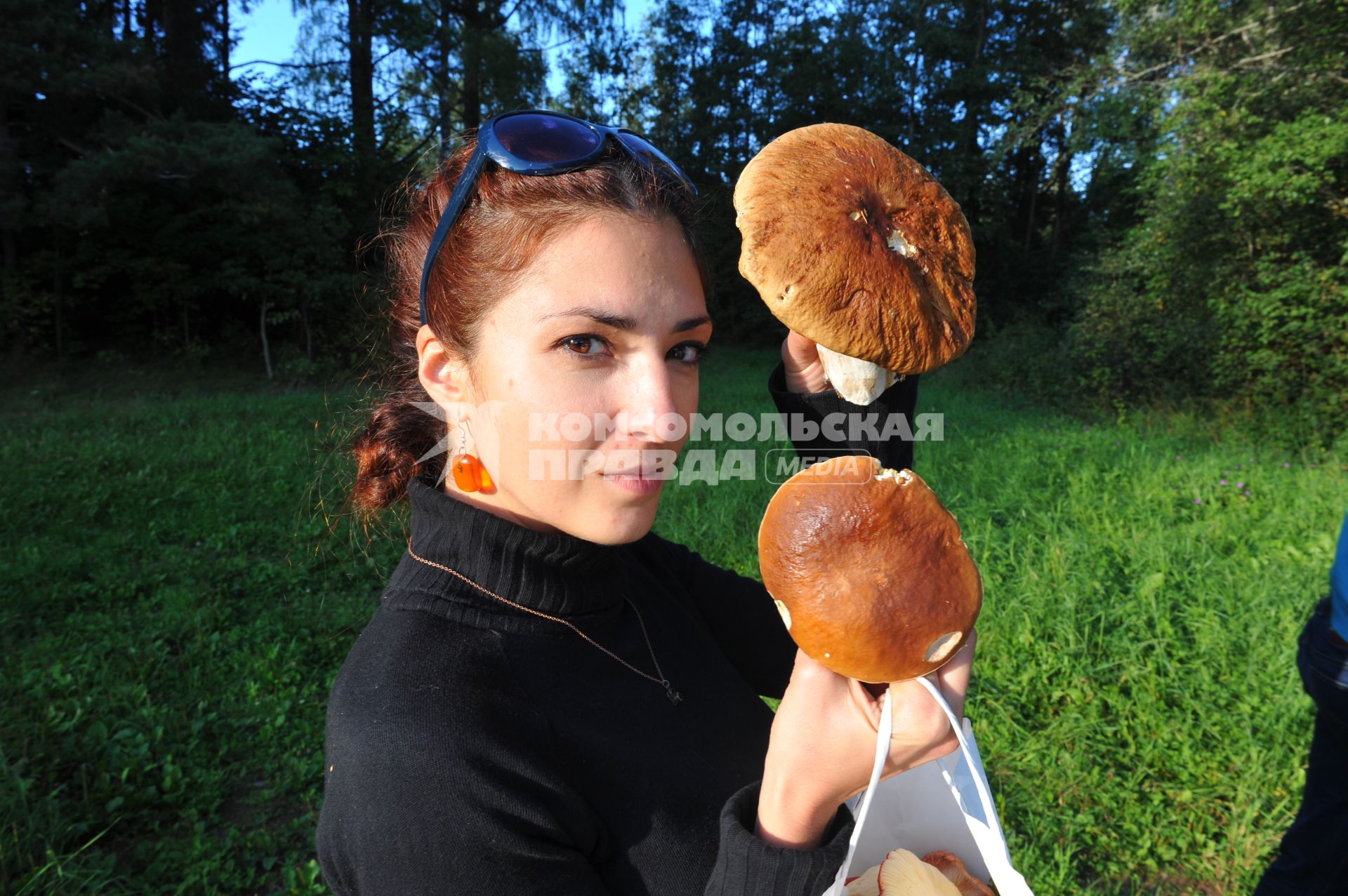 Девушка держит в руках белые грибы.