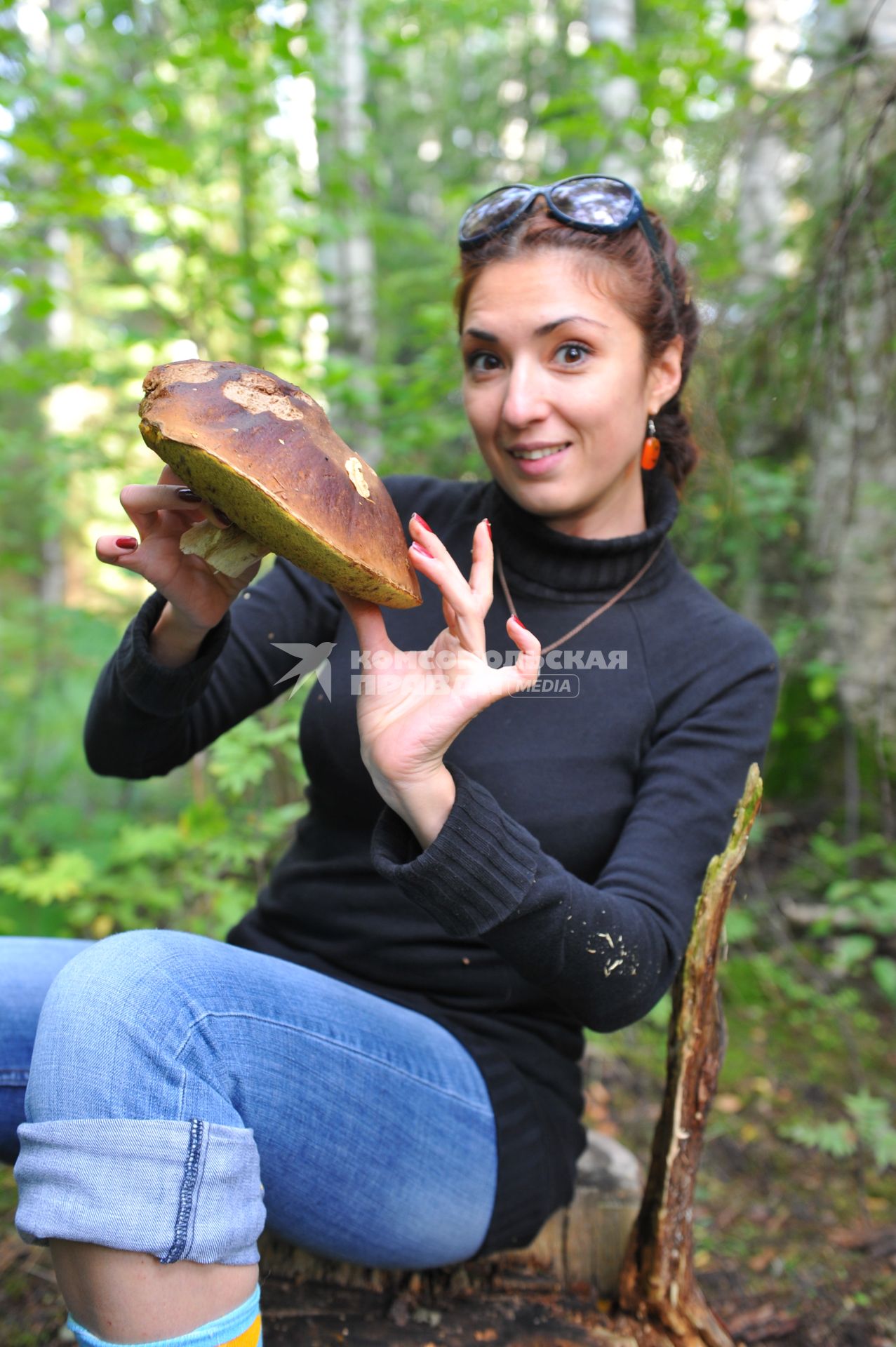 Девушка собирает грибы в лесу.