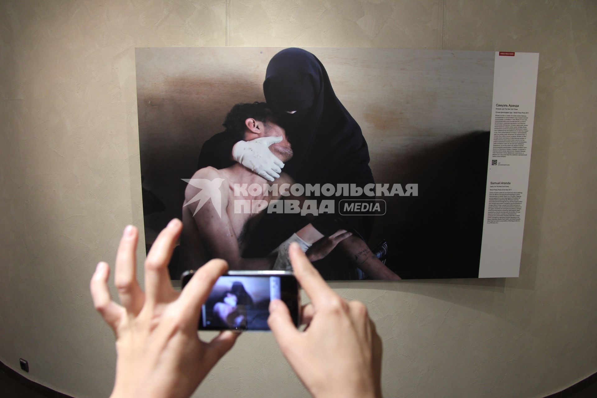 Фотовыставка `World press photo 2012`. На снимке: Посетитель выставки фотографирует на телефон Iphone работу Самуэля Аранда.