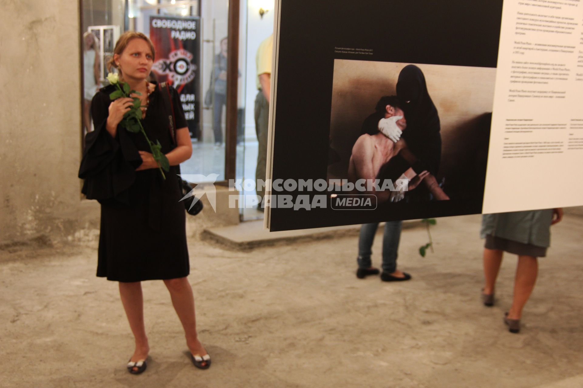 Фотовыставка `World press photo 2012`. На снимке: Девушка с цветком белой розы осматривает экспозицию выставки.