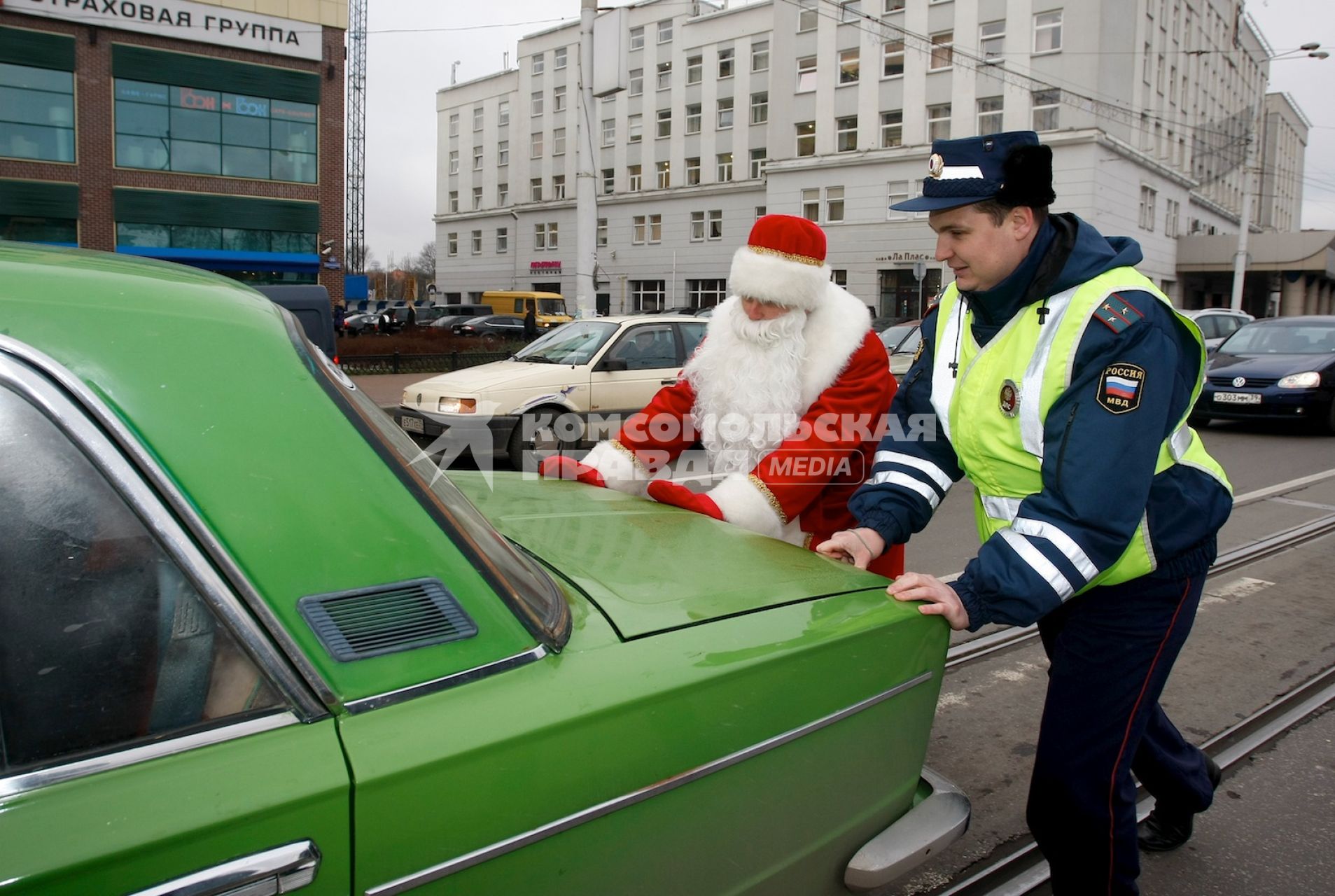 Полицейский помогает деду морозу отбуксировать автомобиль.