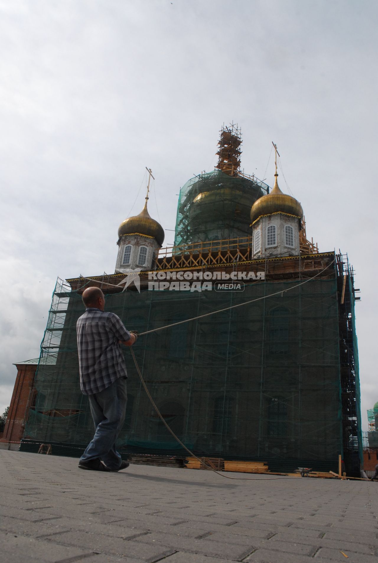 Ремонт Успенского собора на территории тульского кремля. Рабочий тянет канат с доской на фоне собора.