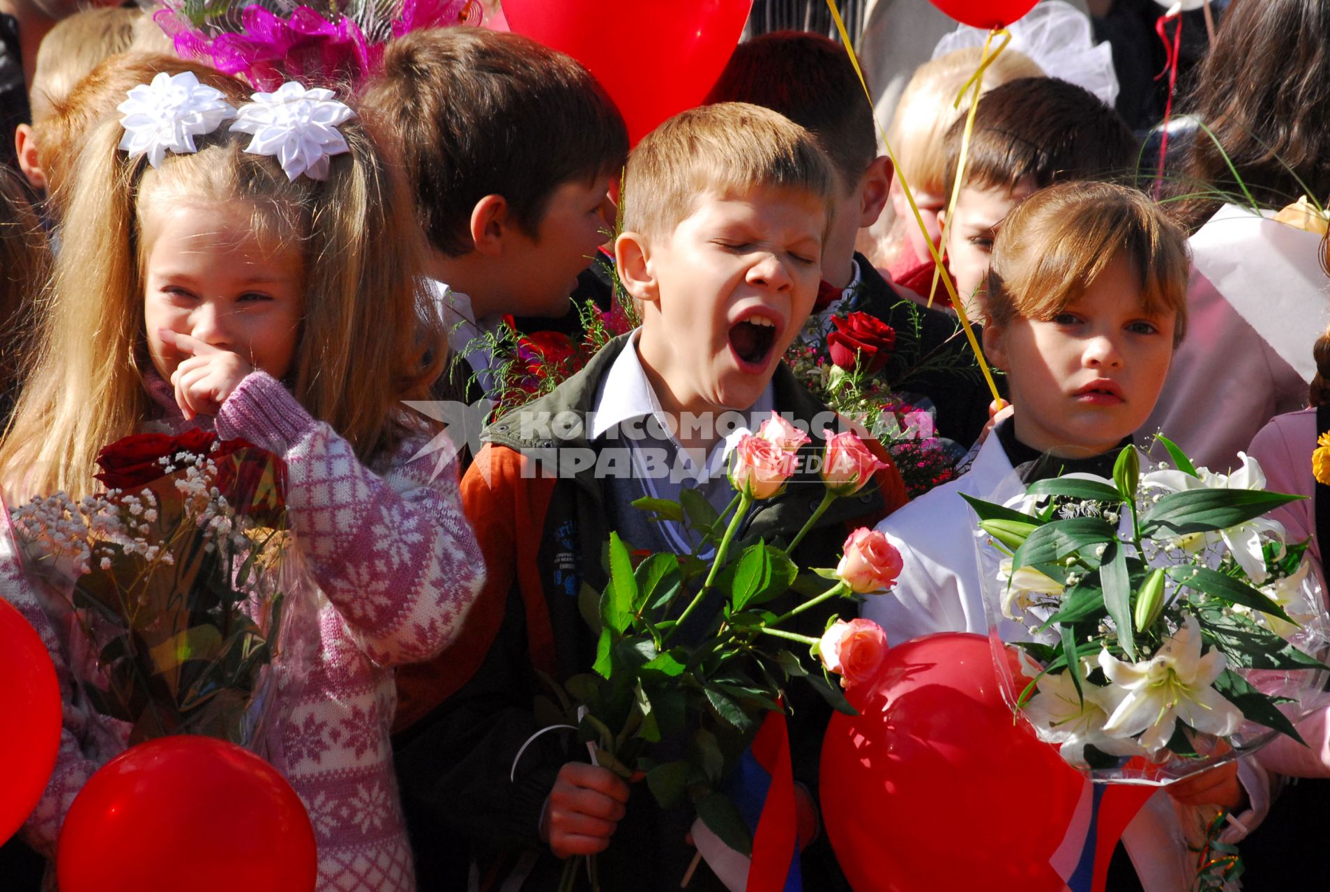 Утренняя линейка. Зевающий первоклассники с цветами.