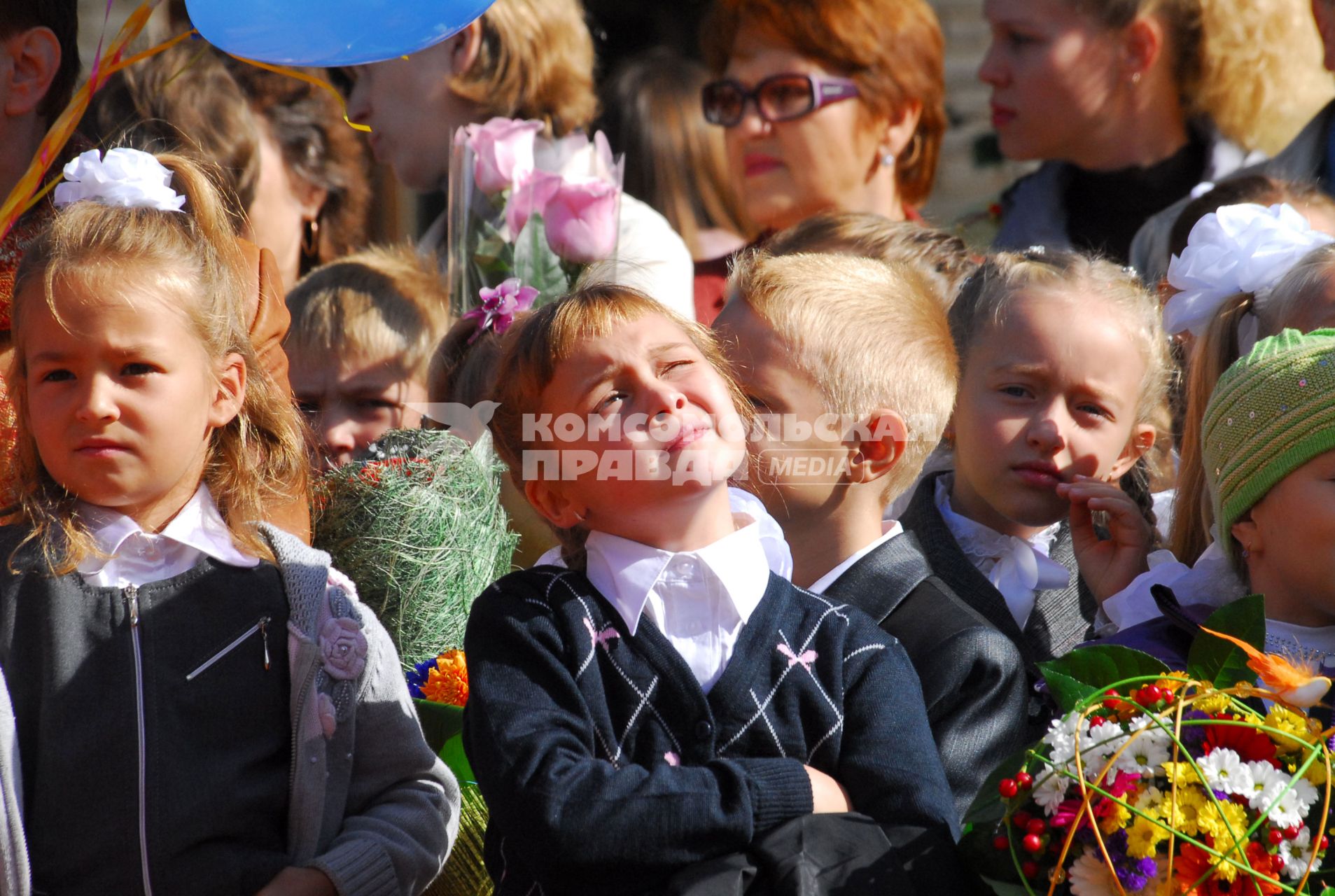 Девочка задумалась на утренней линейке.