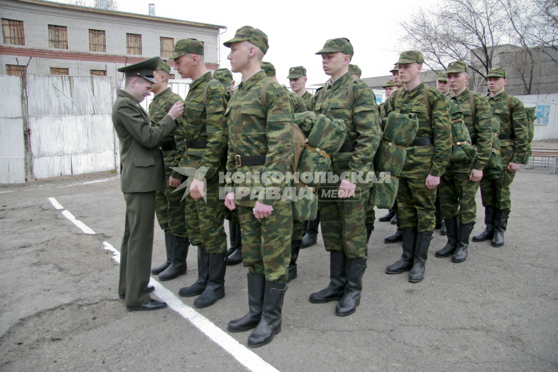 В краевом призывном пункте офицер поправляет форму на новобранце.