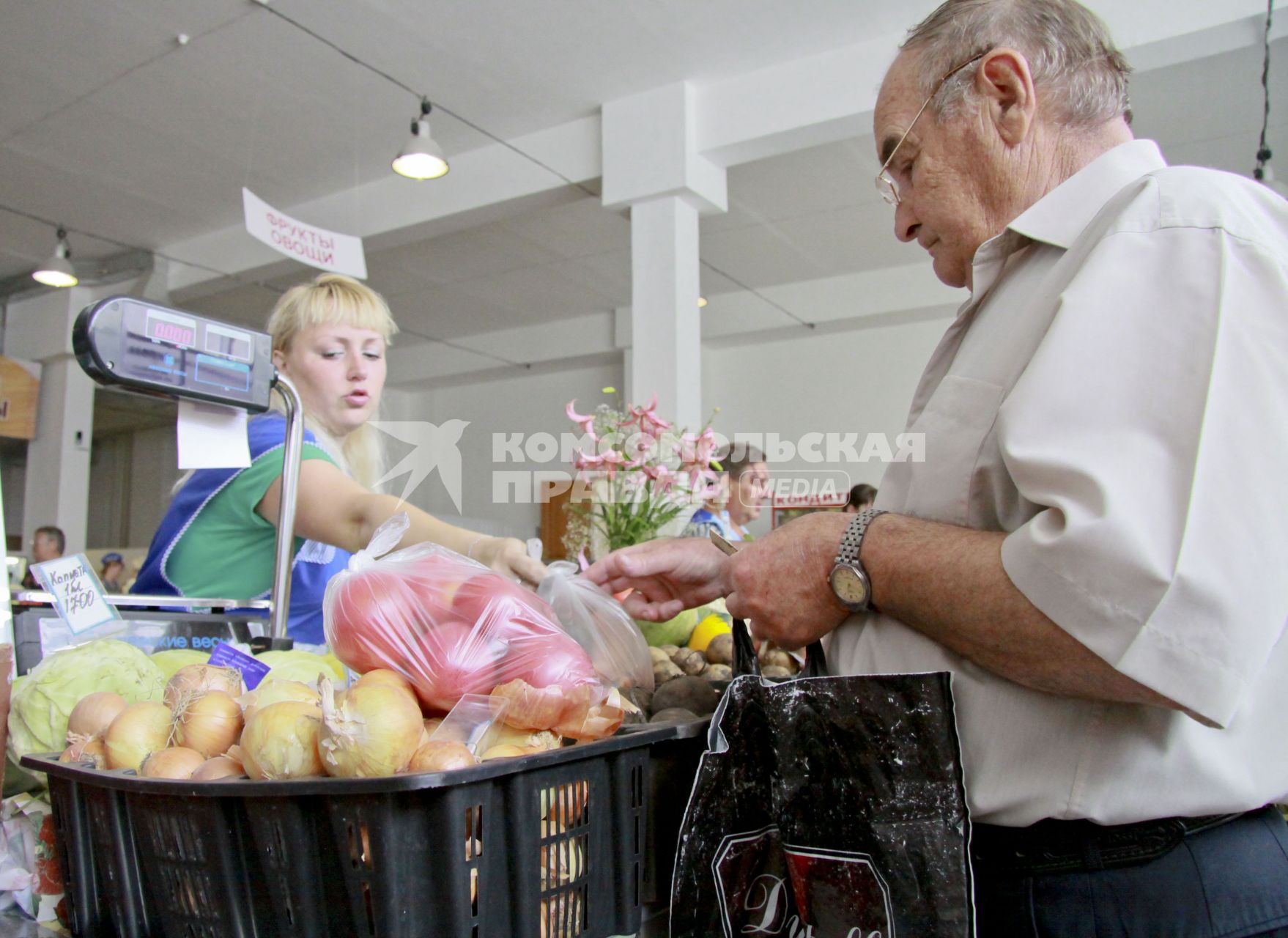 Женщина торгует овощами на рынке.