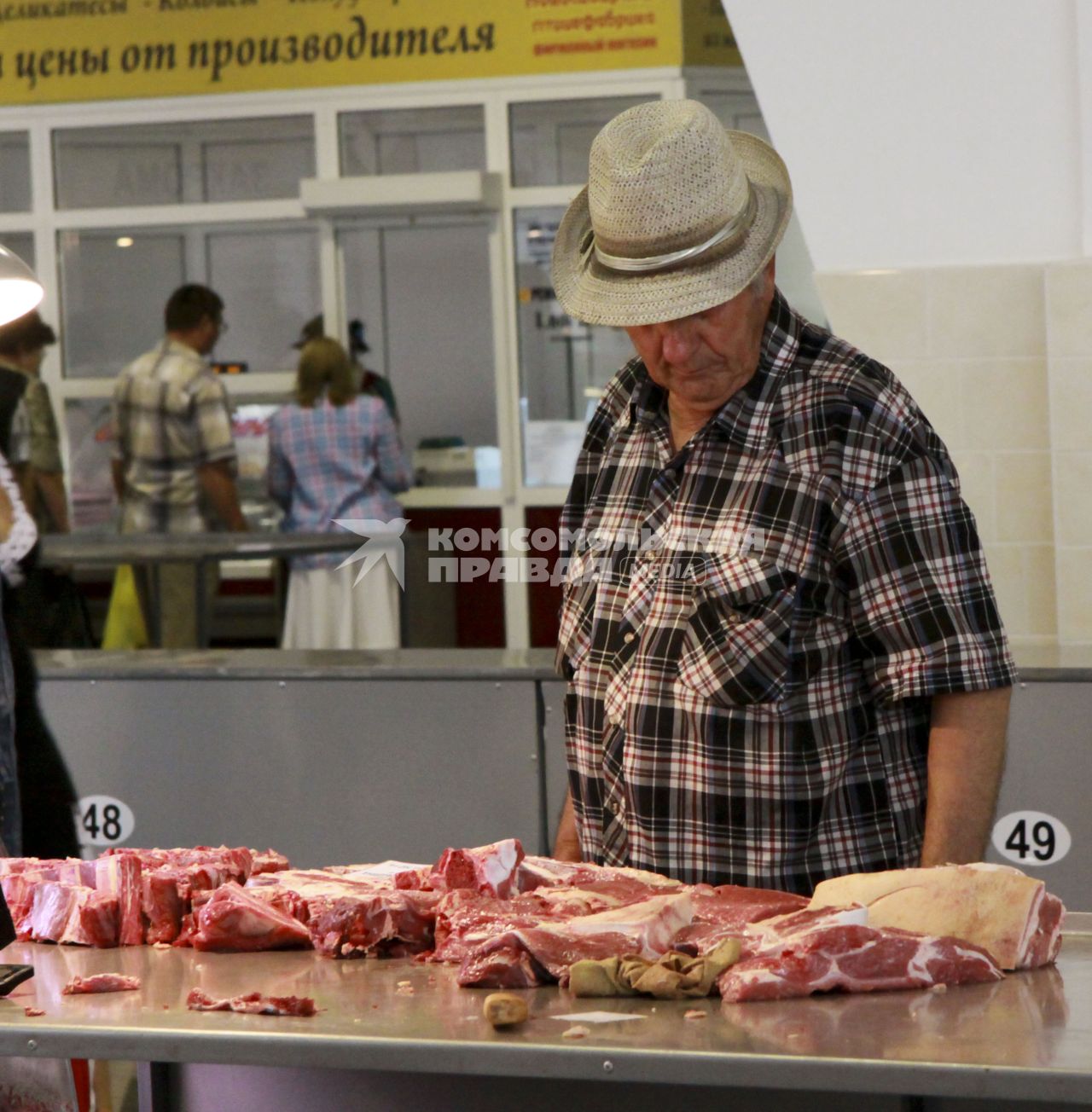 Покупатель присматривается к тавару в мясном ряду на рынке.