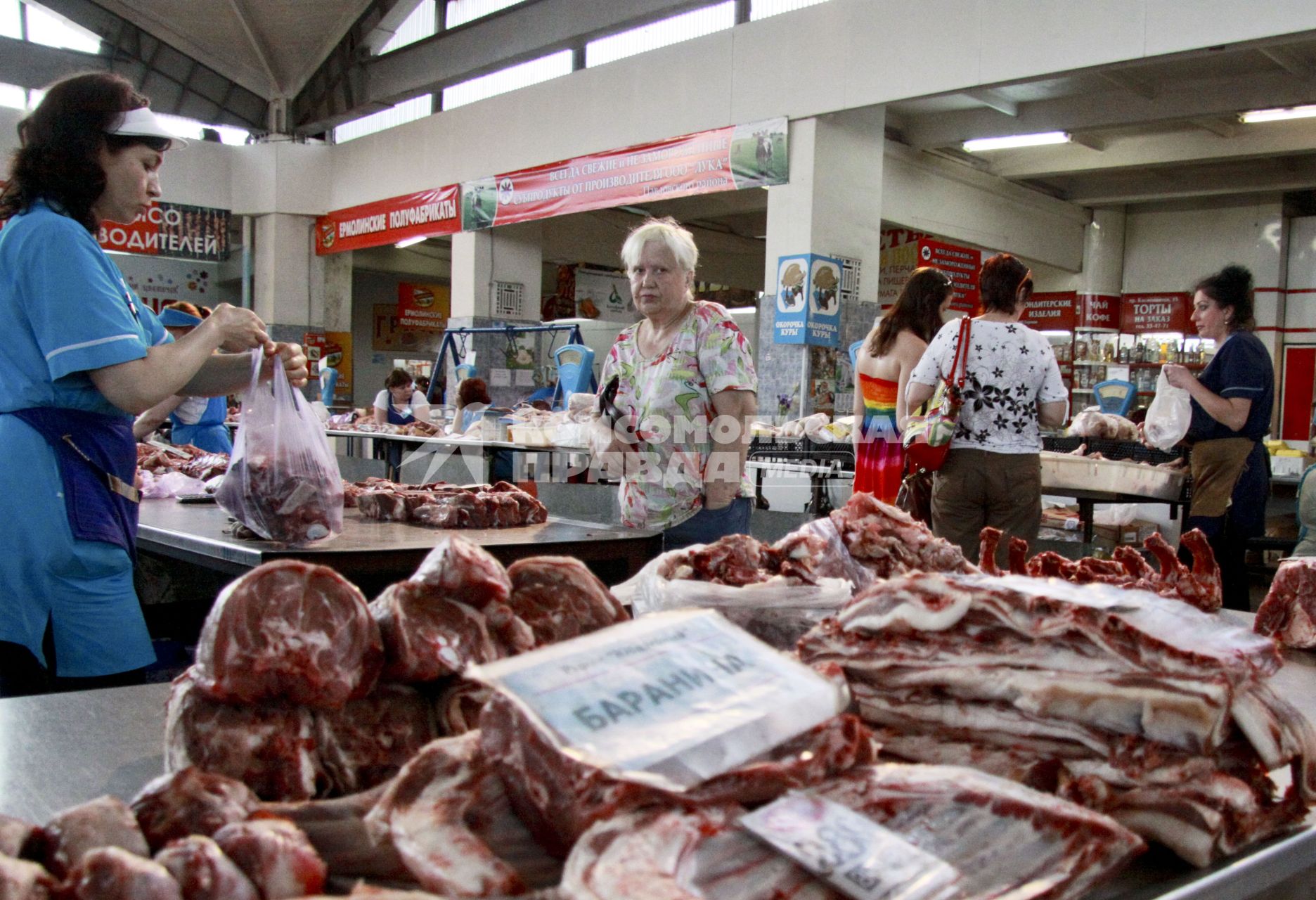 Женщина торгует на рынке мясом.
