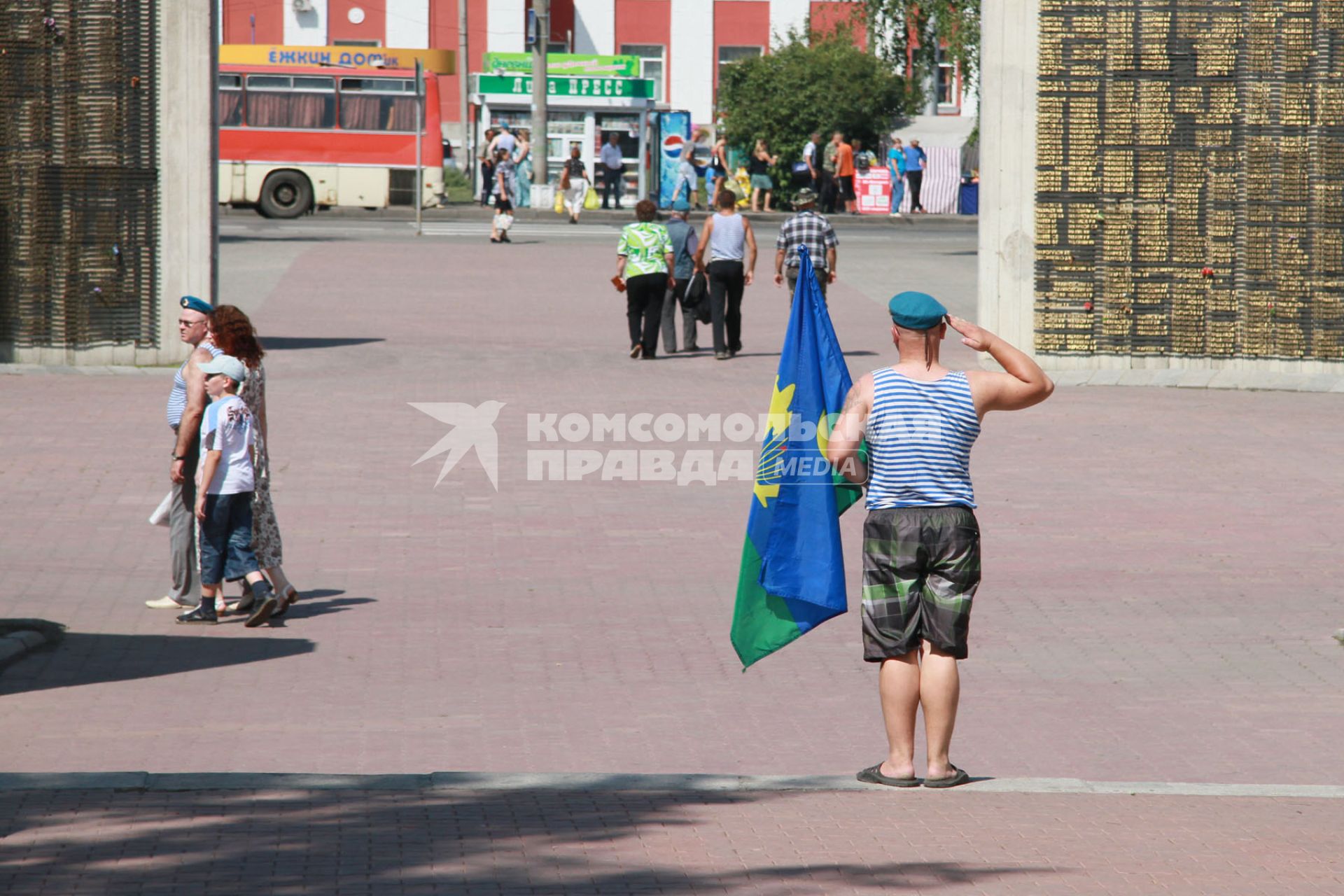 Десантник с флагом ВДВ отдает честь у мемориала.