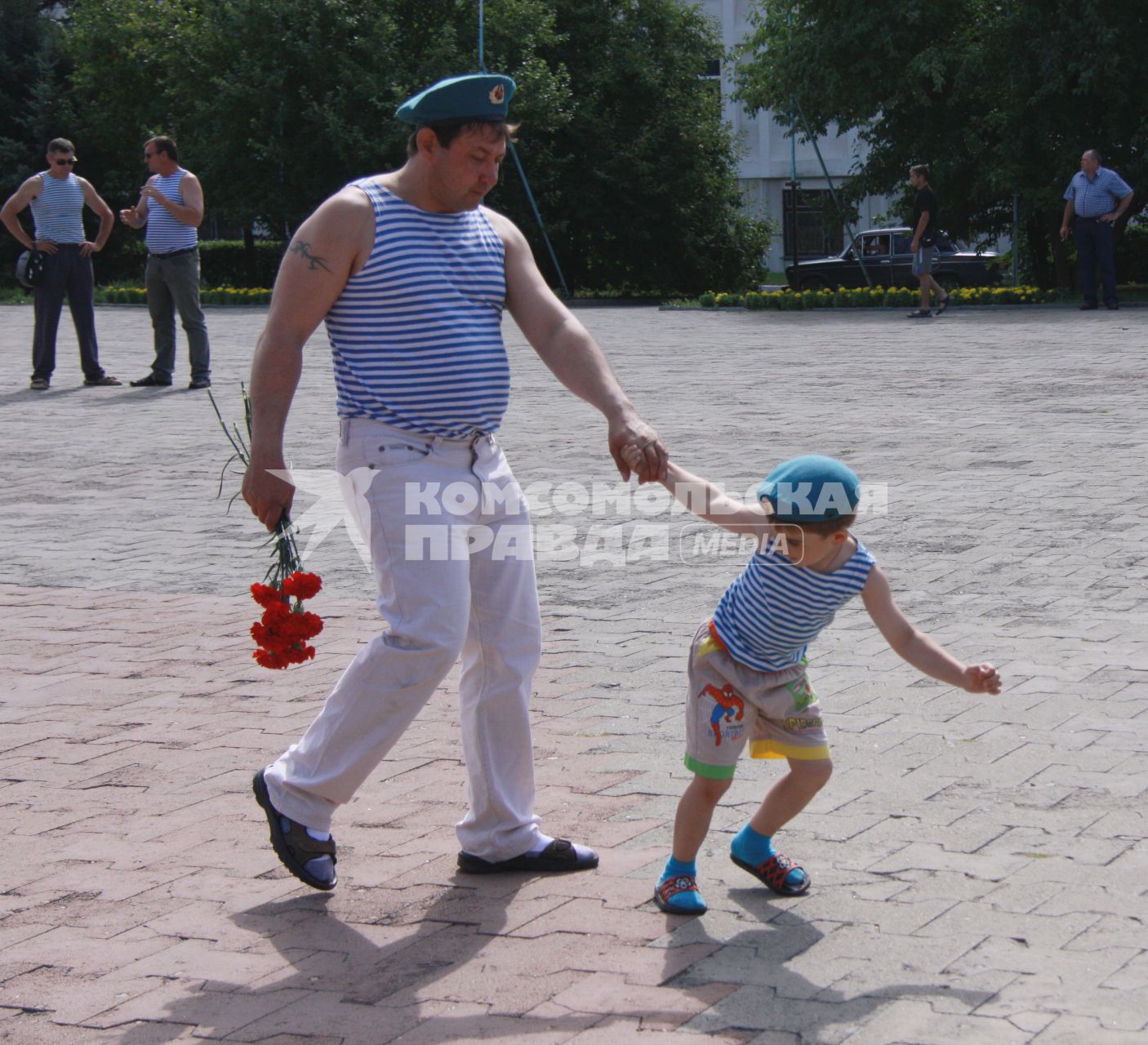 Мальчик в берете и тельняшке тащит за руку папу десантника.