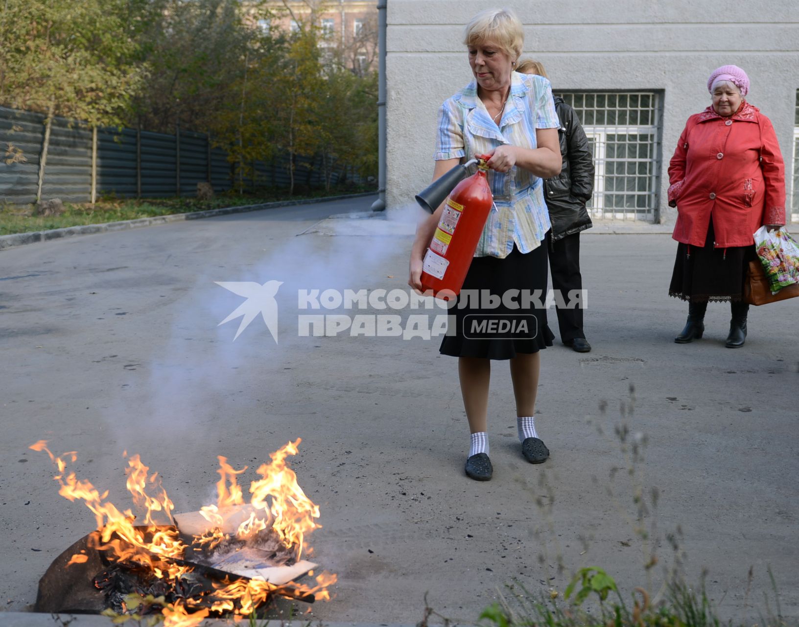 МЧС проводит тренировку по тушению пожара и ликвидации возгораний. На снимке: женщина тушит пламя из огнетушителя.