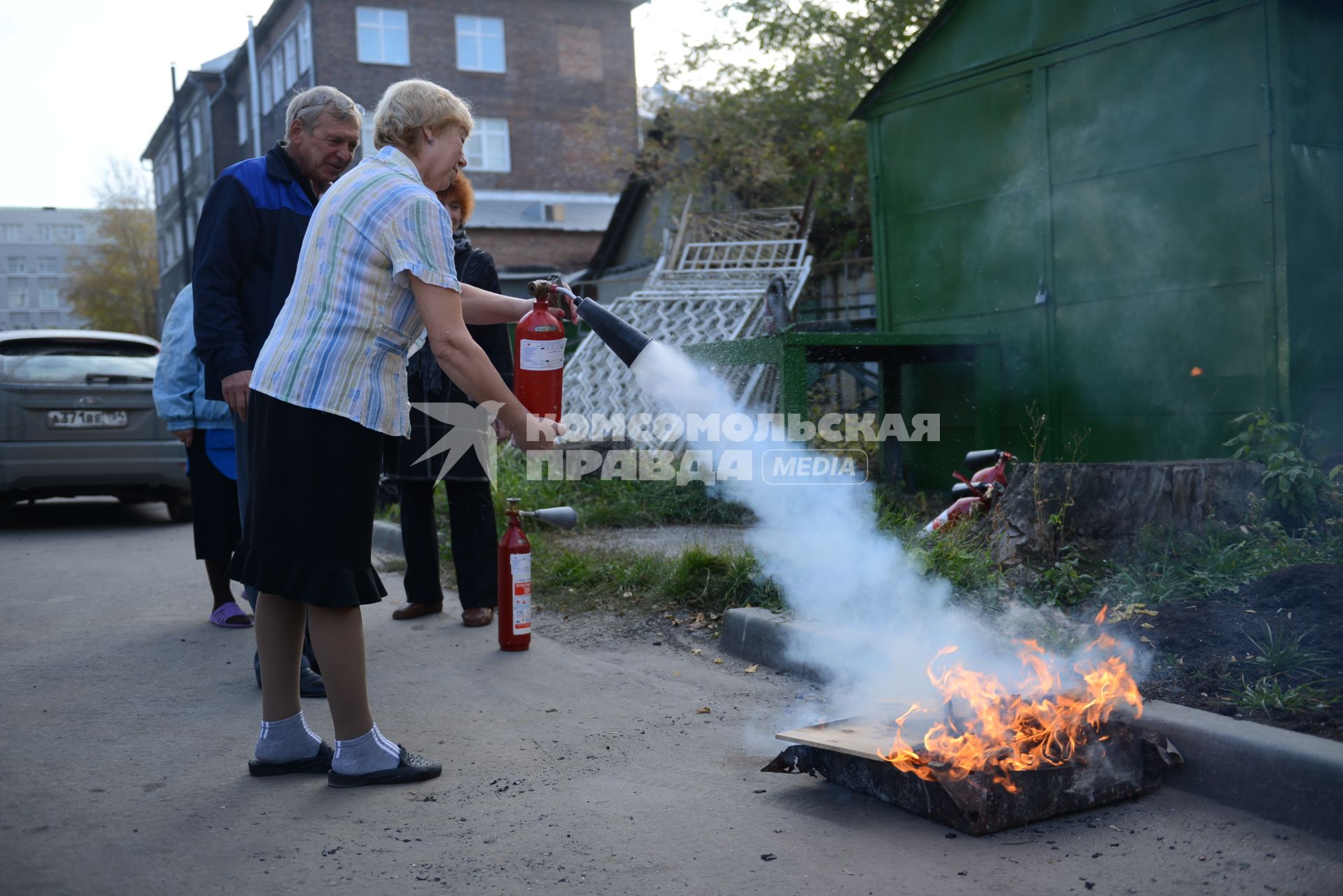 МЧС проводит тренировку по тушению пожара и ликвидации возгораний. На снимке: женщина тушит пламя из огнетушителя.