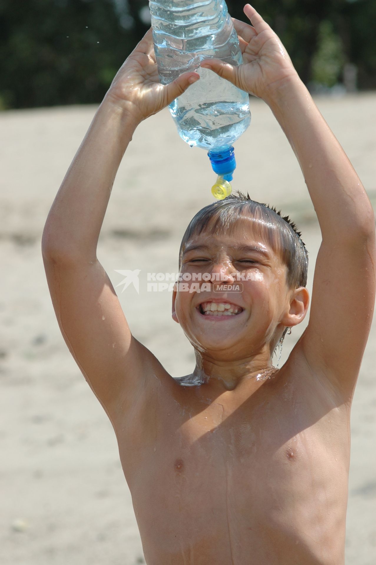 Мальчик поливает себя водой из бутылки.