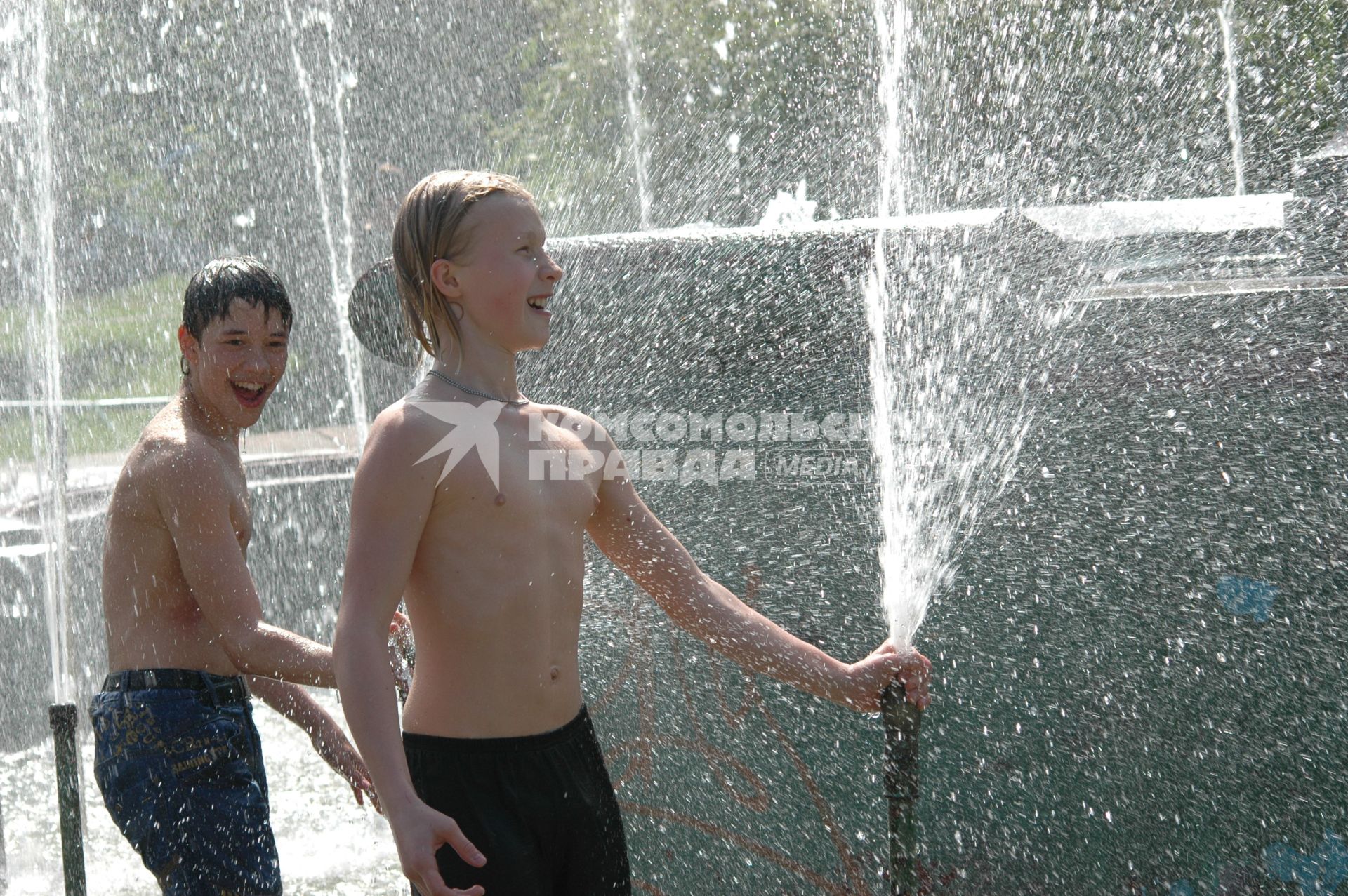 Дети играют в фонтане с водой.