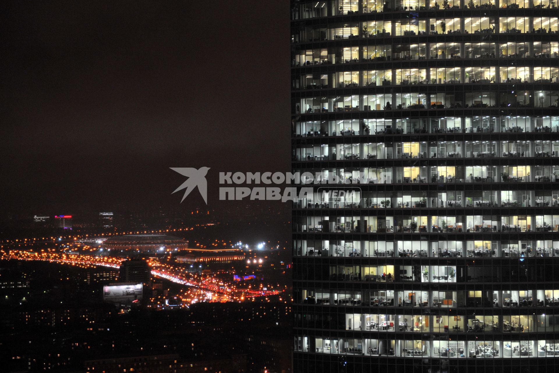 Небоскреб в `Москве-Сити` ночью с видом на стадион `Лужники`.