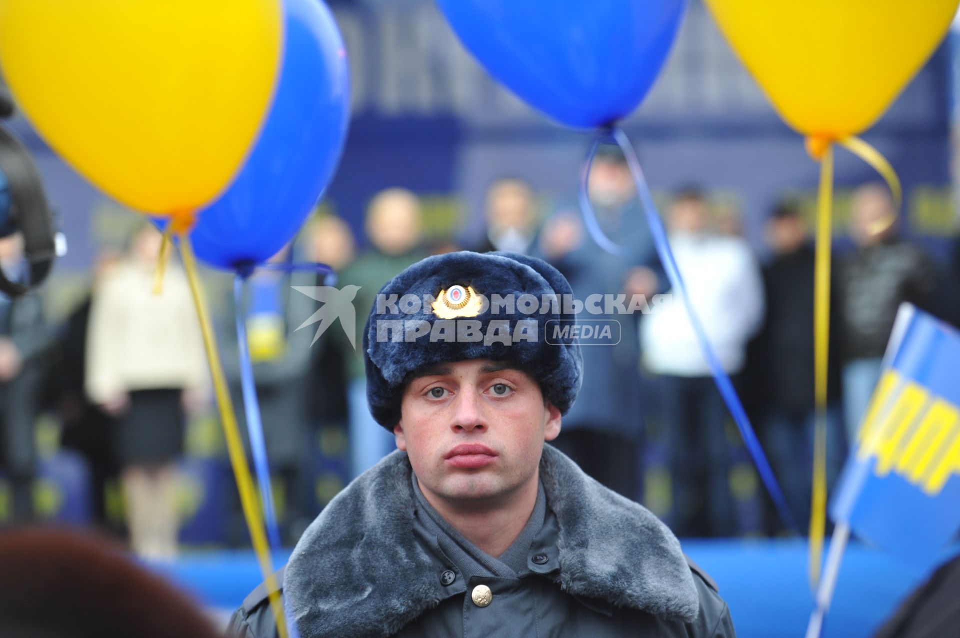 Полицейский стоит в оцеплении на митинге партии `ЛДПР`, рядом с ним висят воздушные шарики.