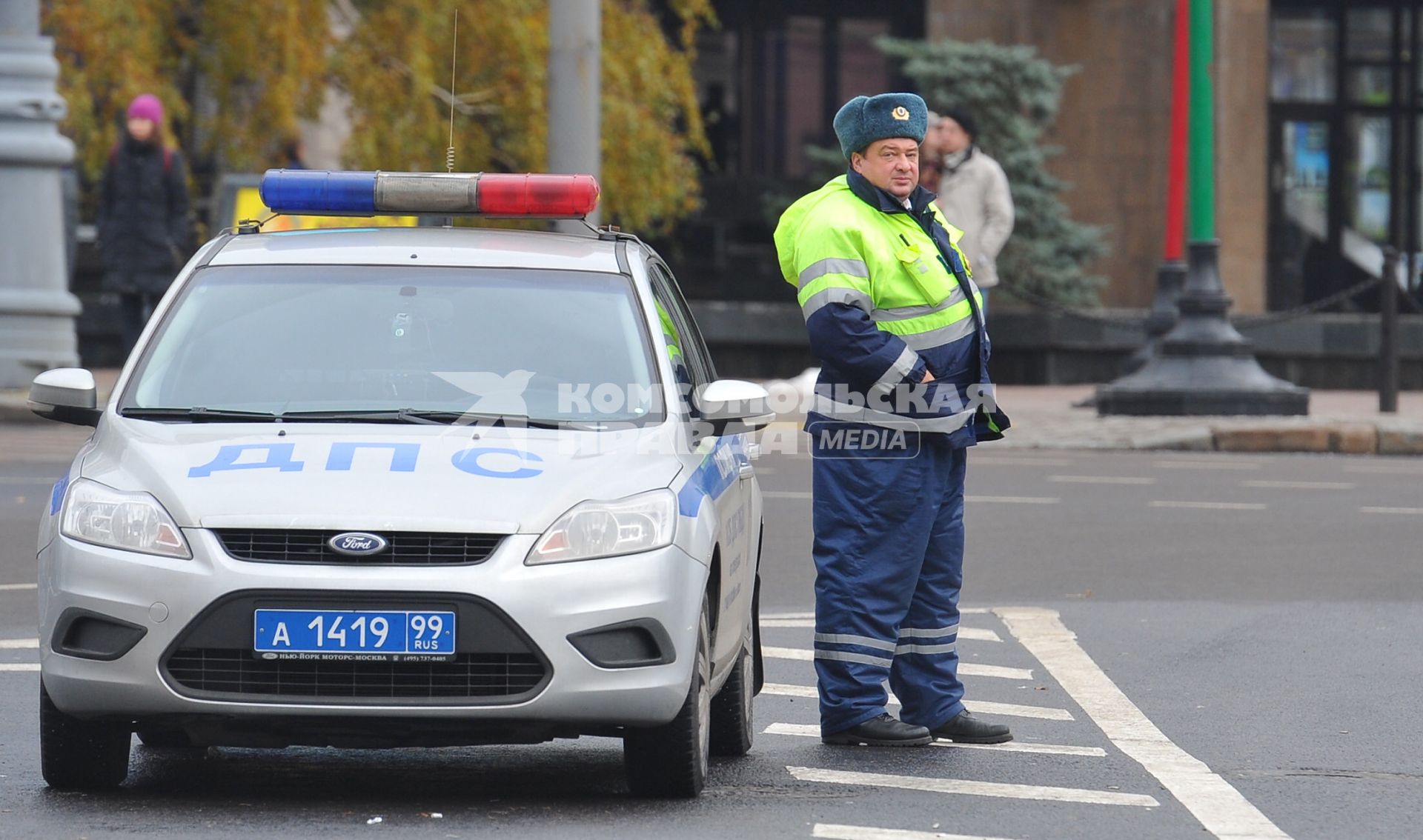 Сотрудник ДПС рядом со служебным автомобилем.