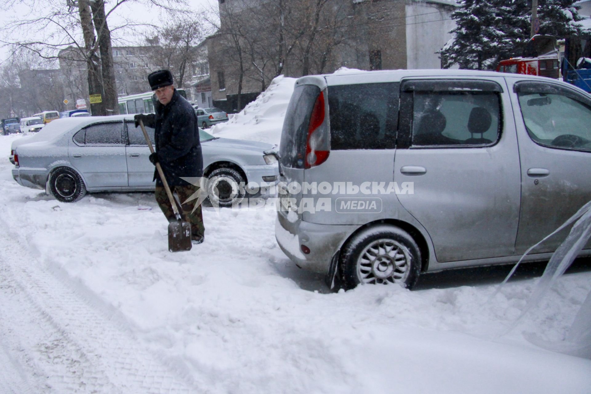 Мужчина откапывает автомобиль после обильного снегопада.