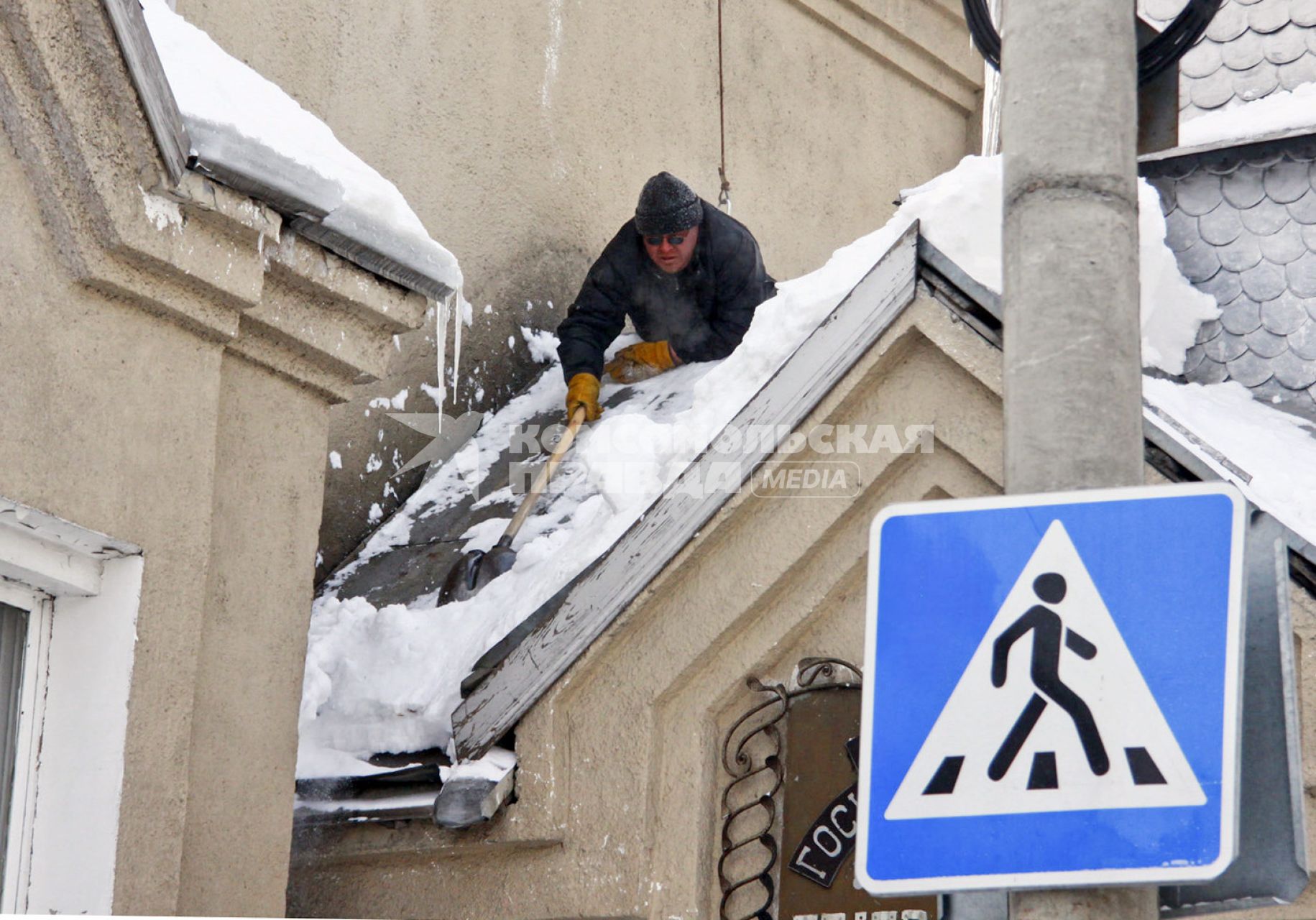 Мужчина очищает крышу от снега.