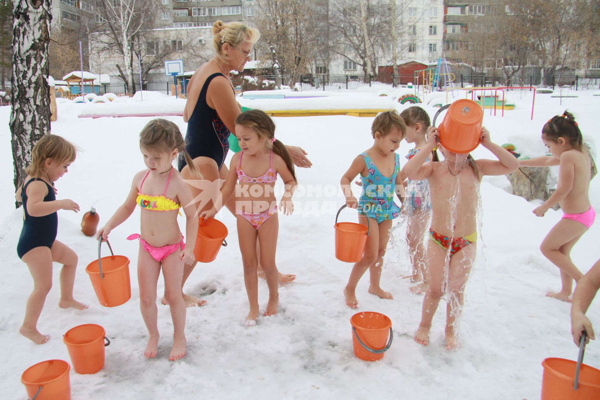 Закаливание в детском саду зимой. На снимке: дети обливаются водой на улице зимой.