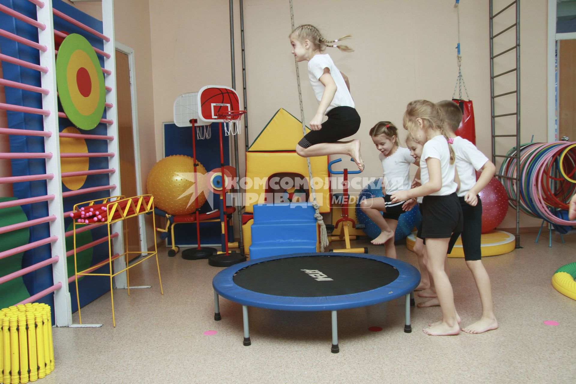 Занятия гимнастикой в детском саду. Дети выполняют упражнения на батуте.