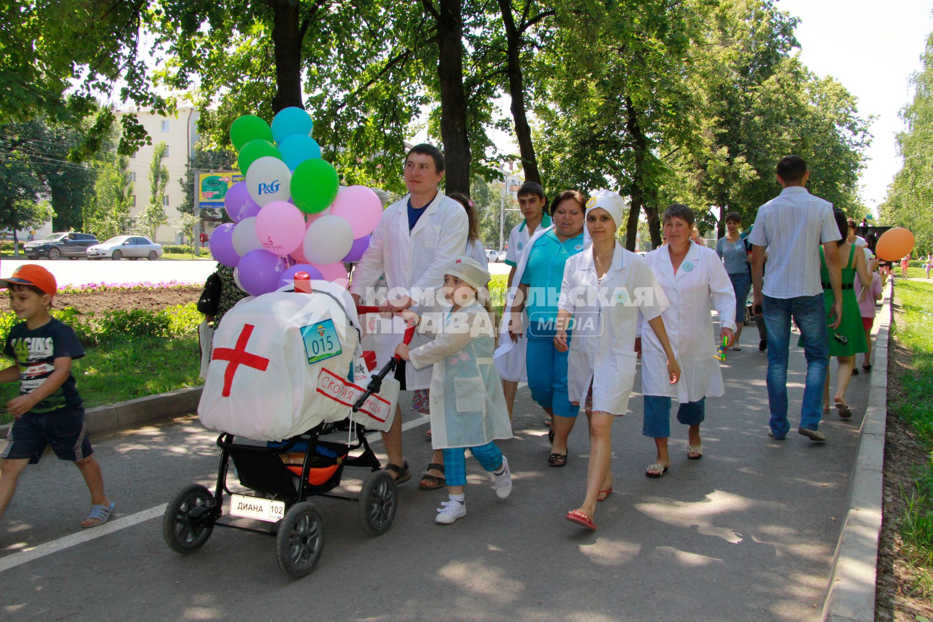 Парад детских колясок в Уфе. На снимке: родители в белых медицинских халатах идут рядом с детской коляской похожей на машину скорой помощи.