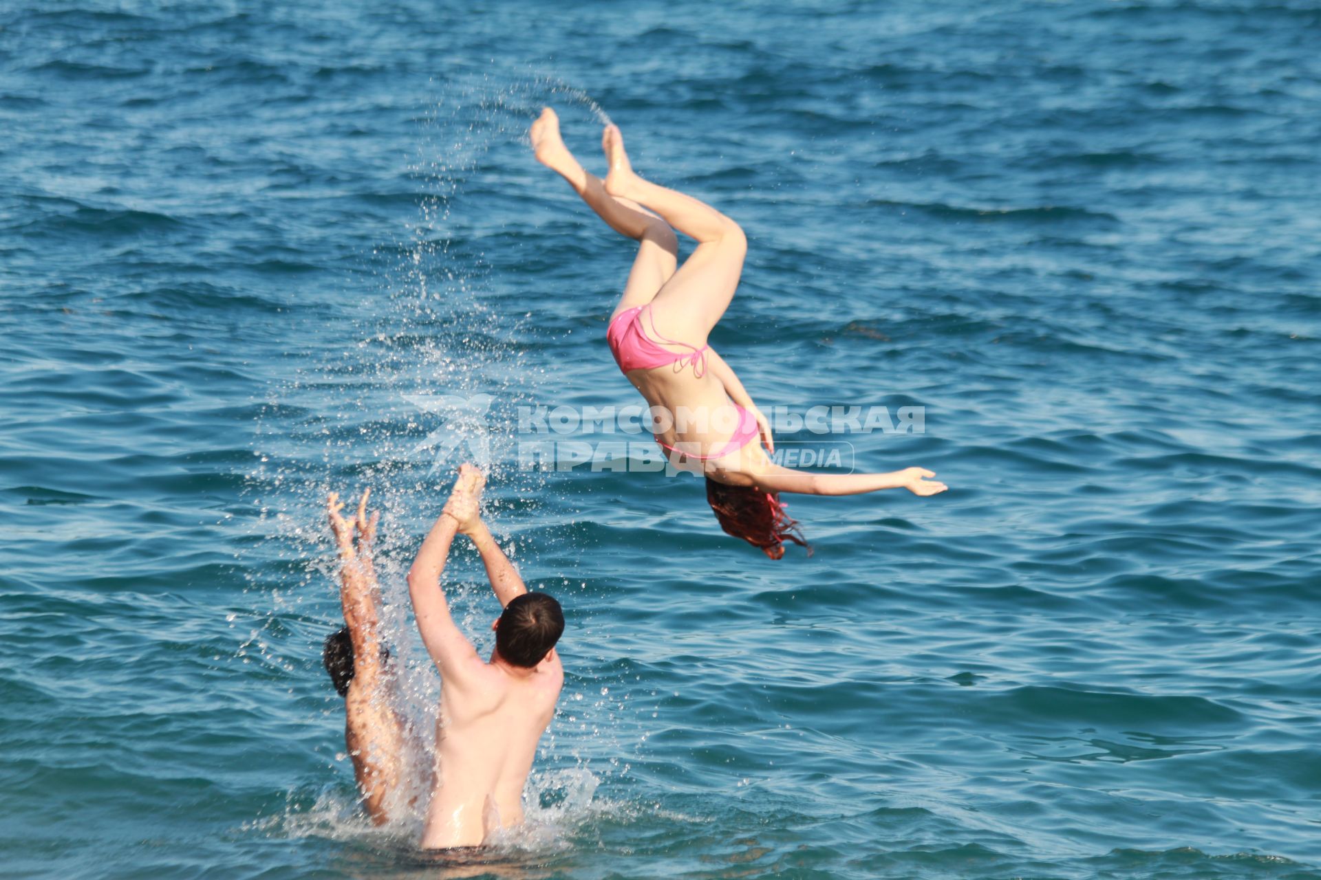 Девушку подкидывают в воду двое подростков.
