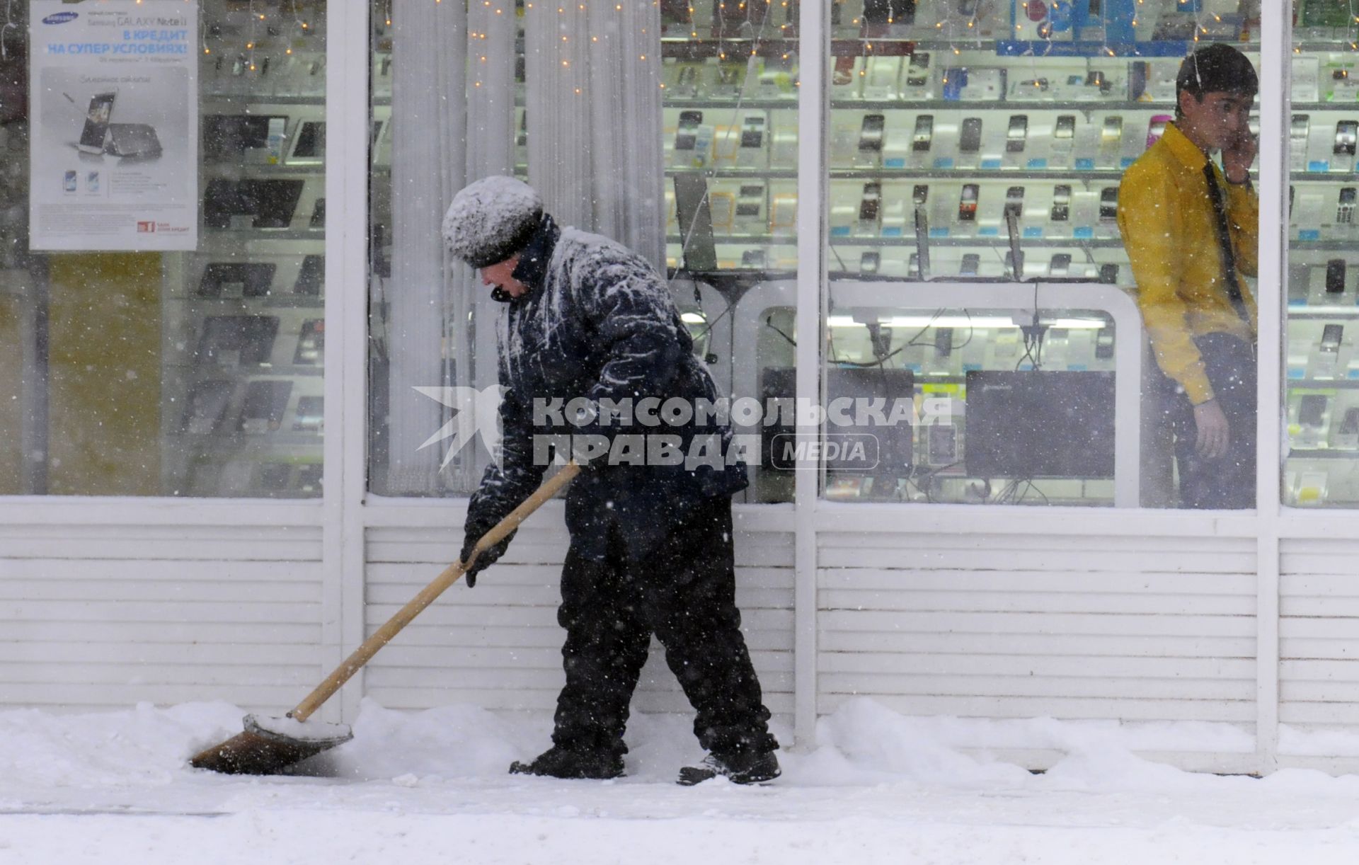 Уборка снега на городской улице. На снимке: дворник с лопатой.