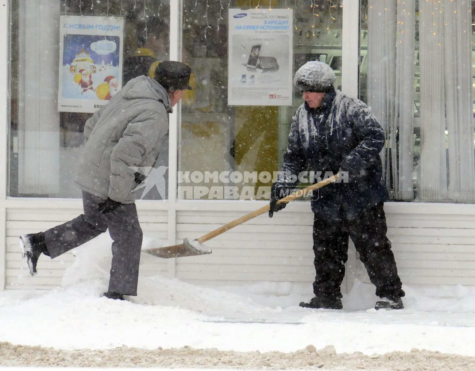 Уборка снега на городской улице. На снимке: дворник с лопатой.