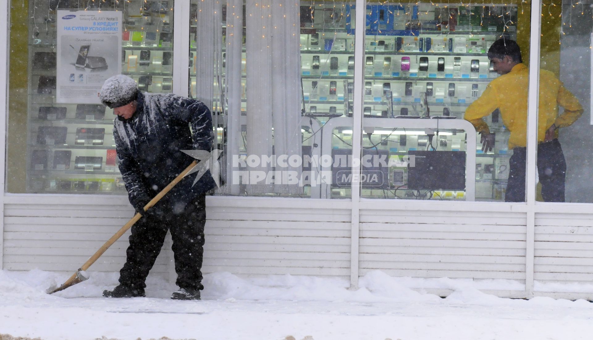 Уборка снега на городской улице. На снимке: дворник с лопатой.