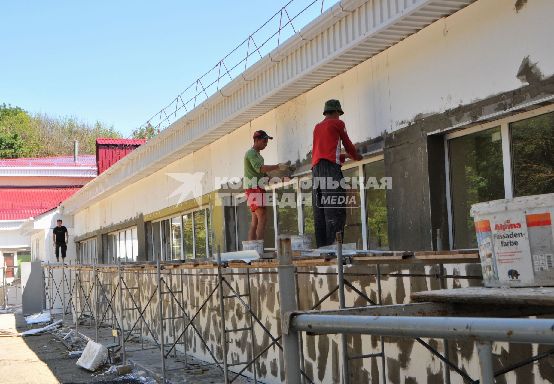 Рабочие ремонтируют фасад здания.