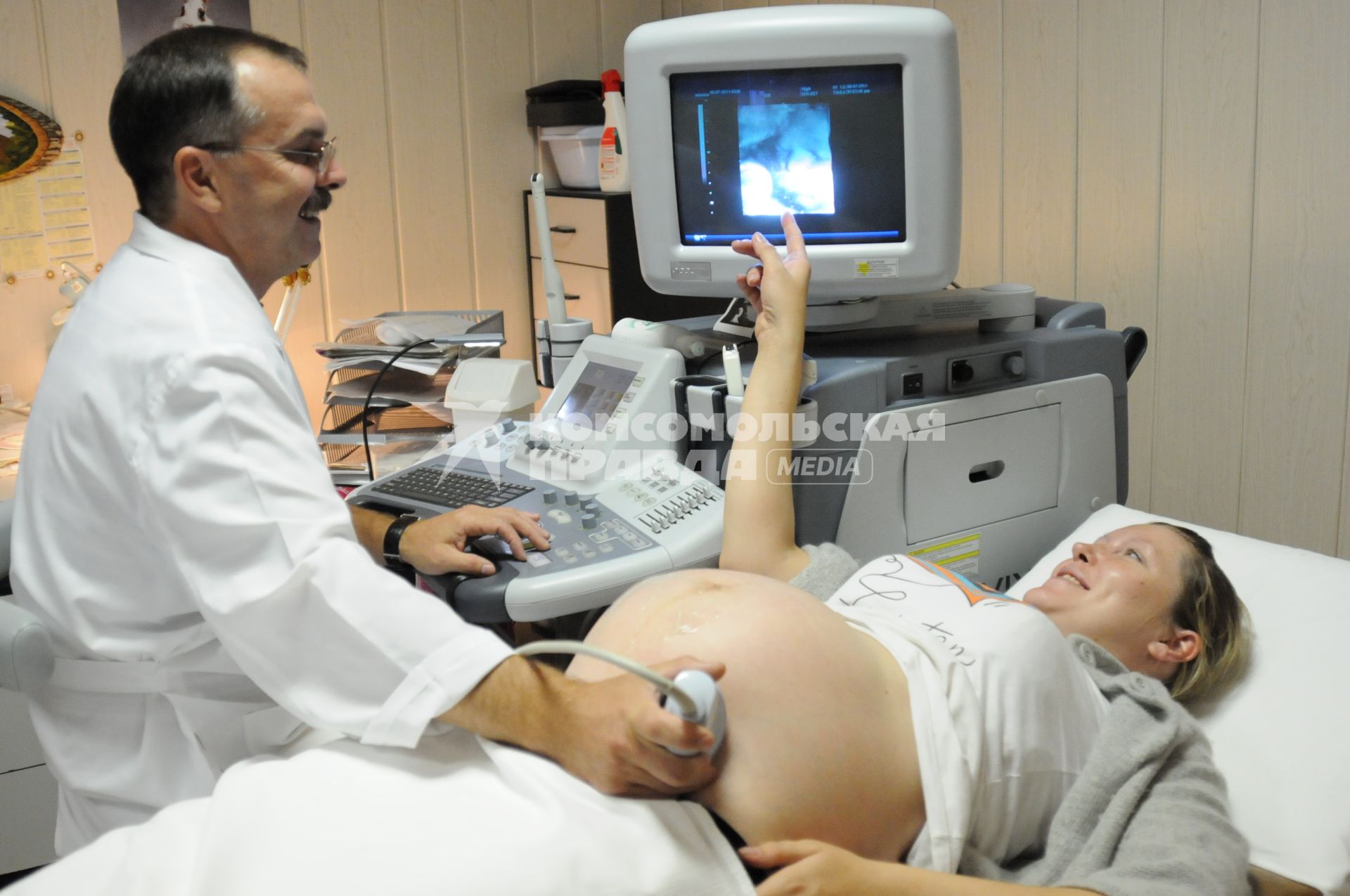 В кабинете УЗИ врач проводит ультразвуковое исследование у беременной женщины.