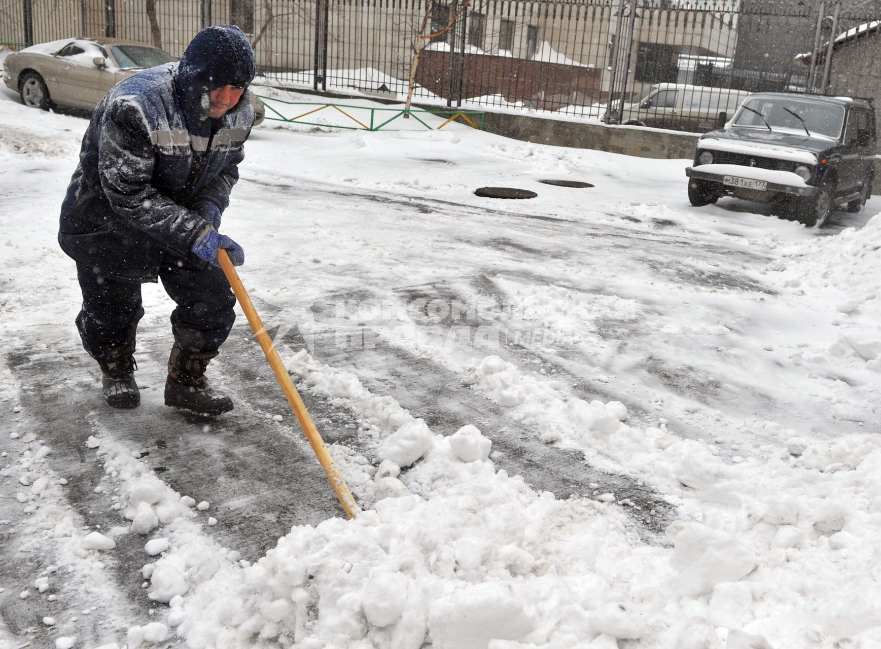 Дворник чистит улицу от снега.