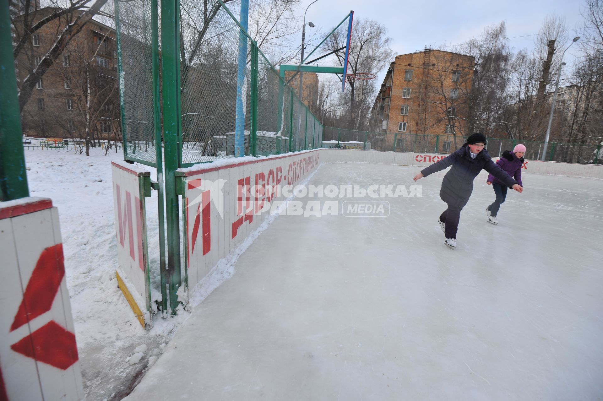 Хоккейная коробка во дворе дома. На снимке: девочки катаются на коньках