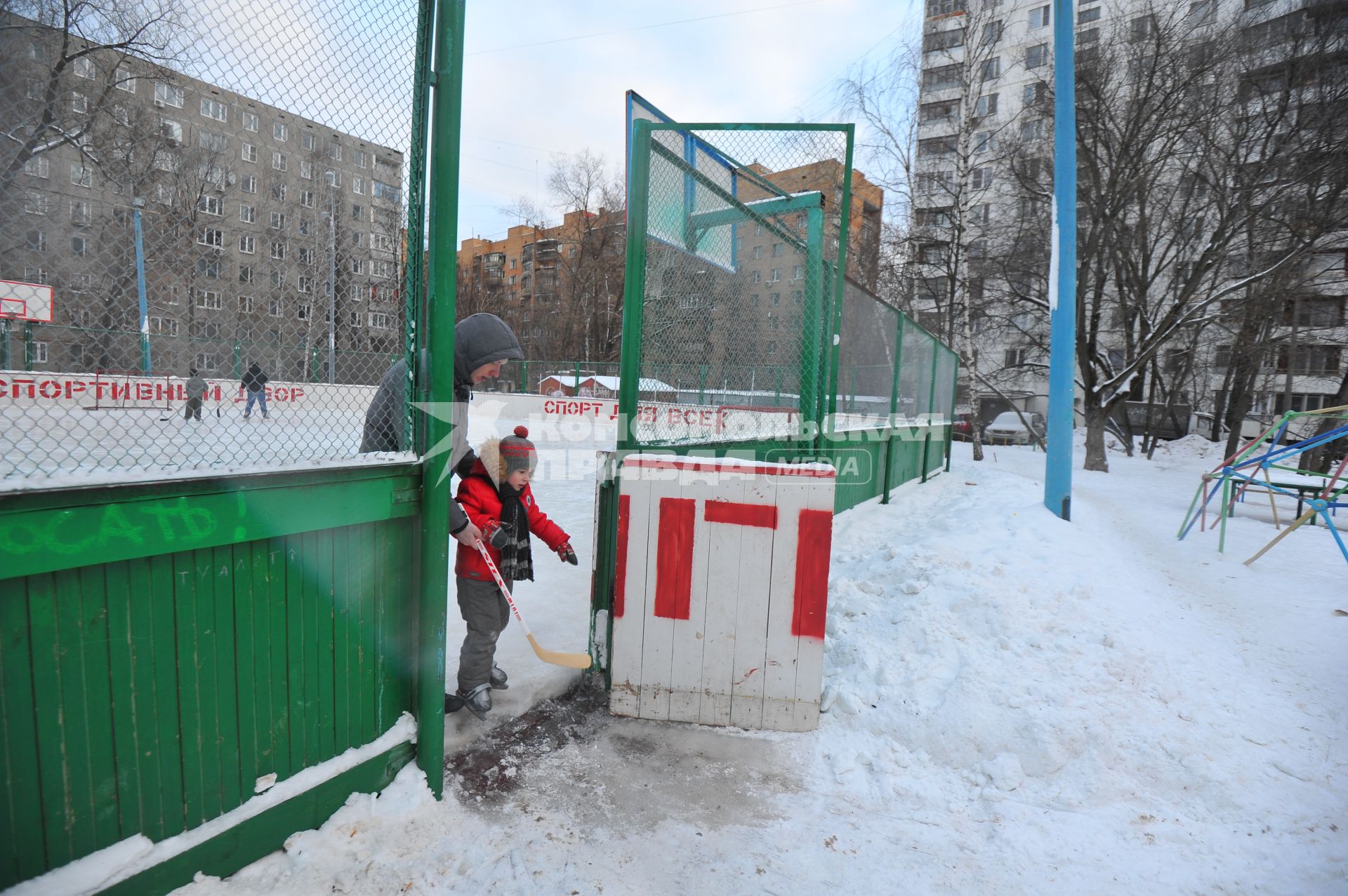 Хоккейная коробка во дворе дома. На снимке: мальчик на коньках с клюшкой в руках