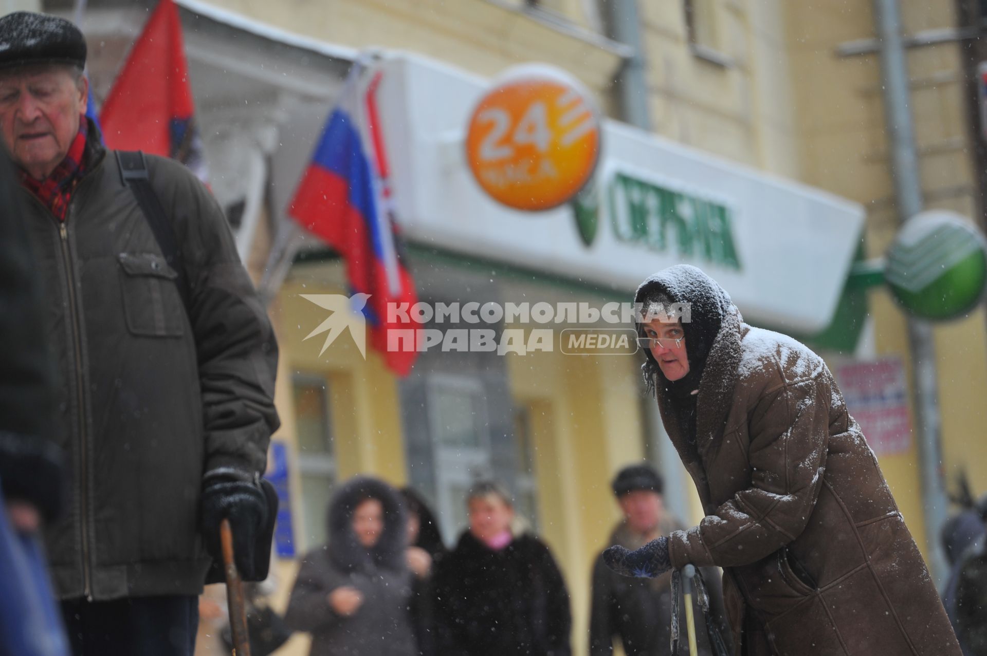 Женщина с протянутой рукой просит милостыню на улице у прохожих людей.