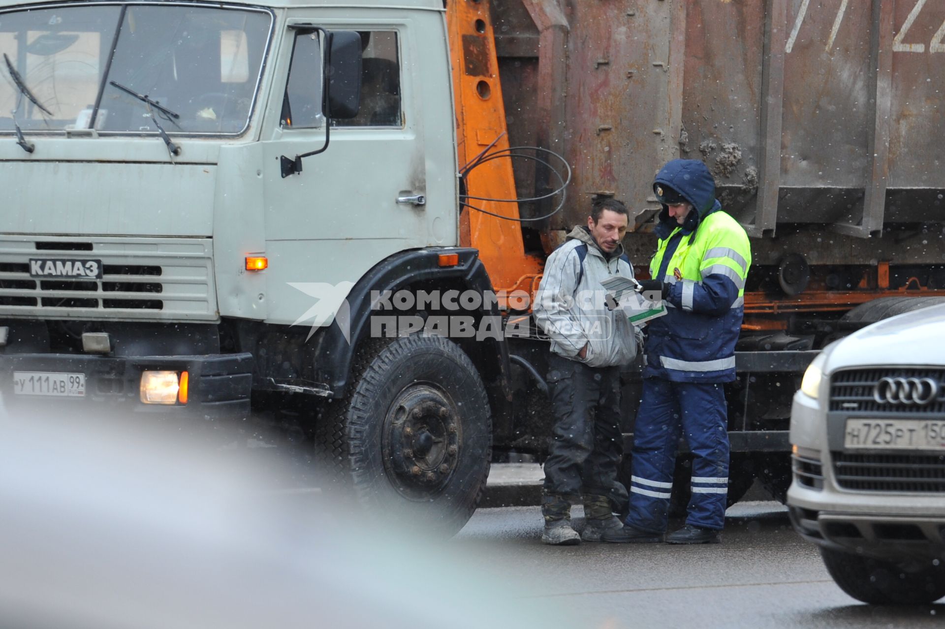 Сотрудник ДПС проверяет документы у водителя КАМАЗа.