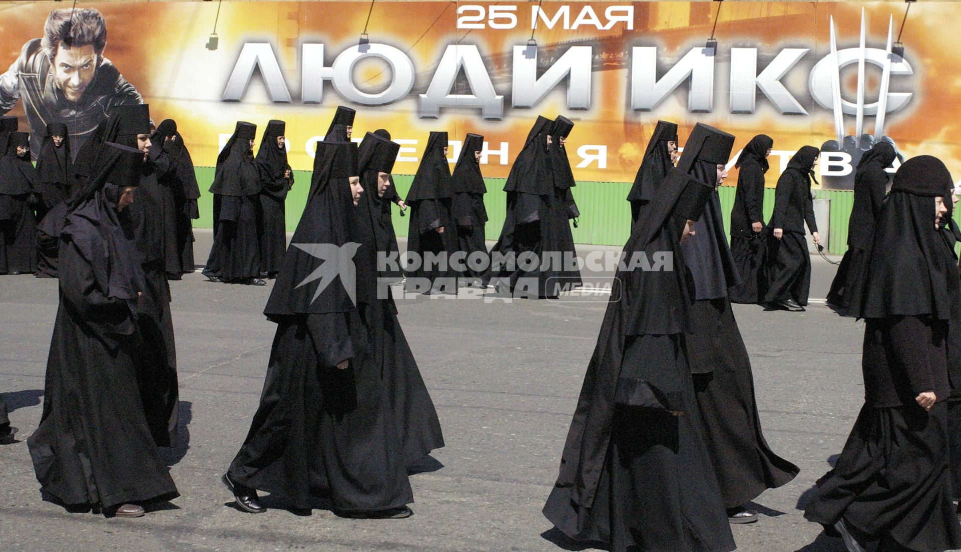 Монашки идут по улице на фоне плаката фильма: `Люди икс`.