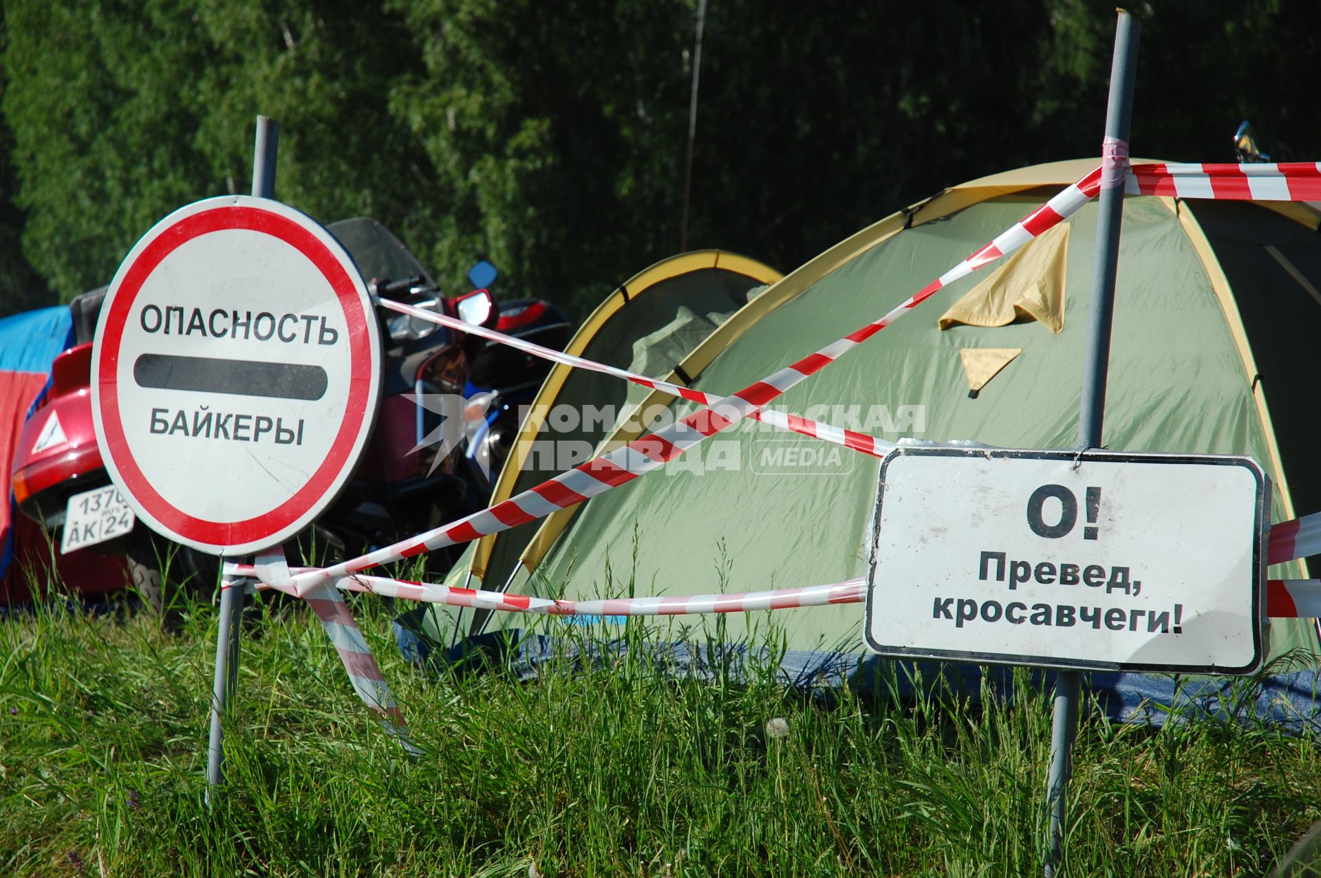 Палаточный лагерь байкеров. Перед лагерем знаки: `Опасность байкеры` и `О! Превед, кросавчеги!`.