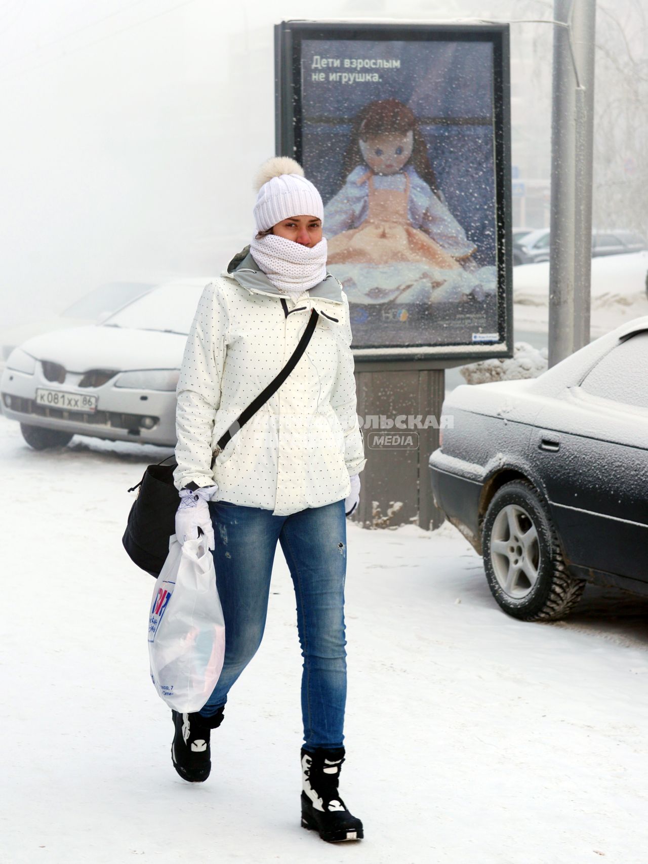 Девушка идет по заснеженной улице.