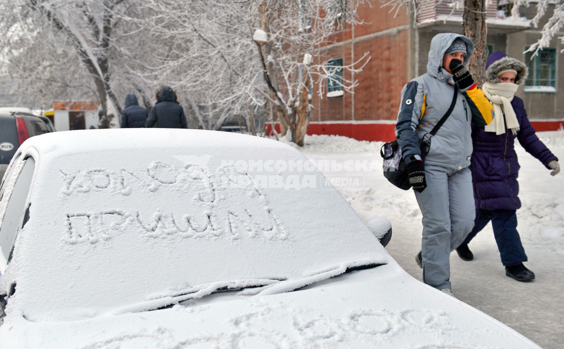 Автомобиль под снегом, на лобовом стекле надпись: `Холода пришли`, мимо проходят пешеходы.