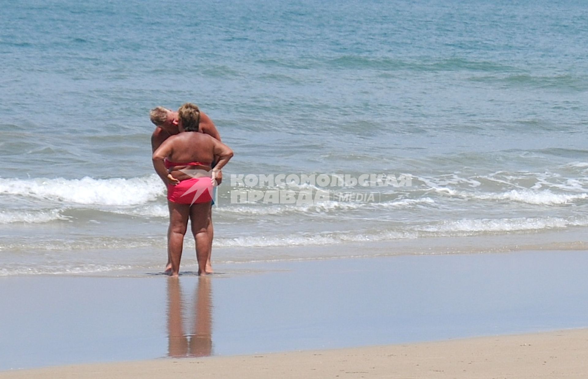 Мужчина и женщина целуются на морском пляже.