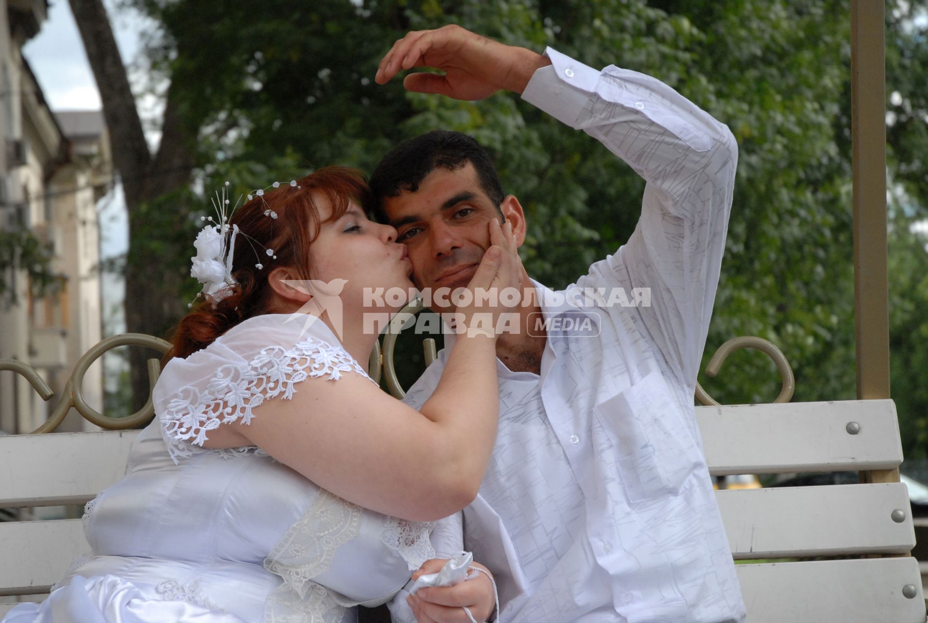 Русская невеста целует жениха кавказца.