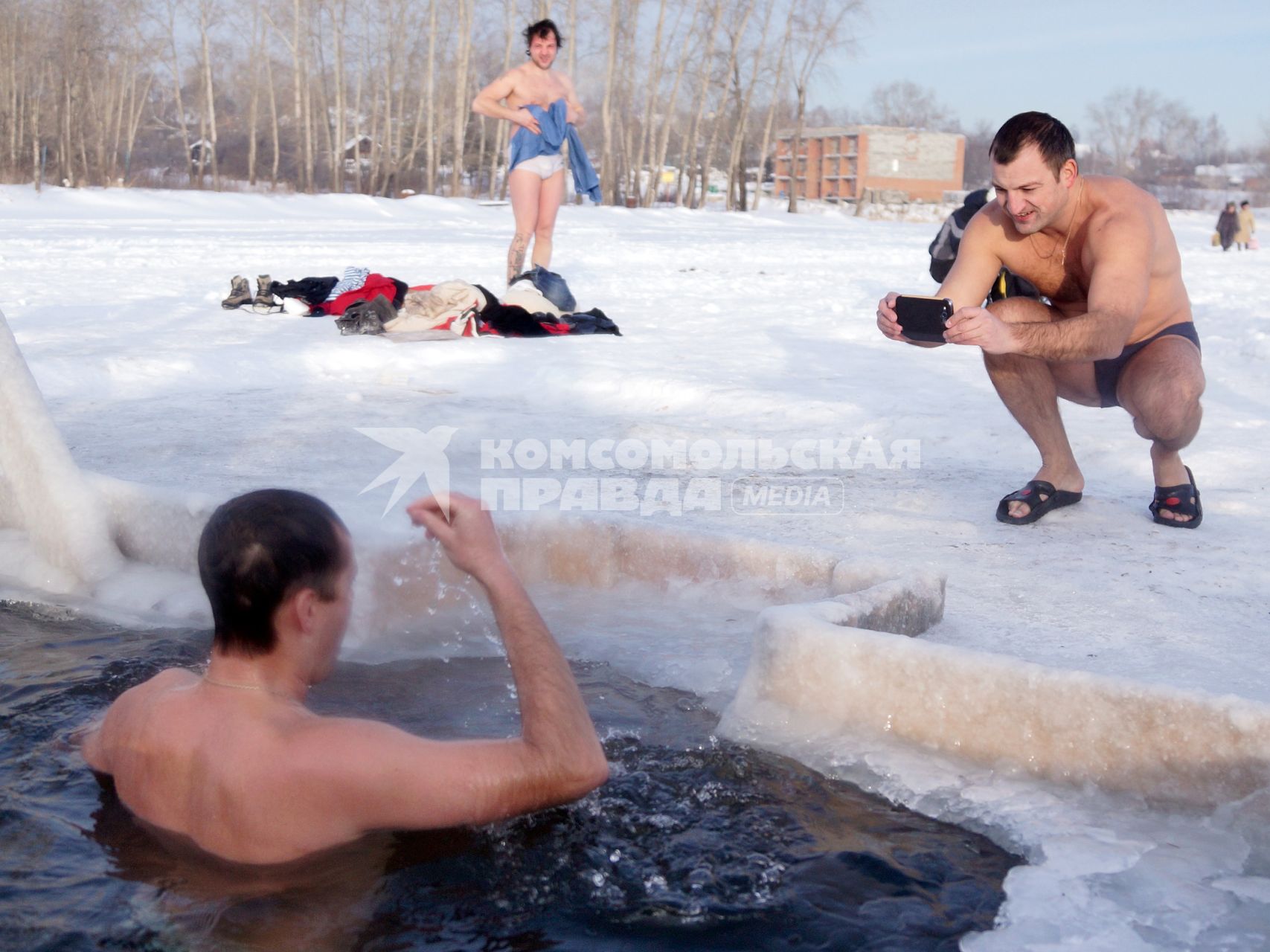 Крещенские купания на озере Шарташ в Екатеринбурге. На снимке: мужчина фотографирует как в проруби ныряет его друг.